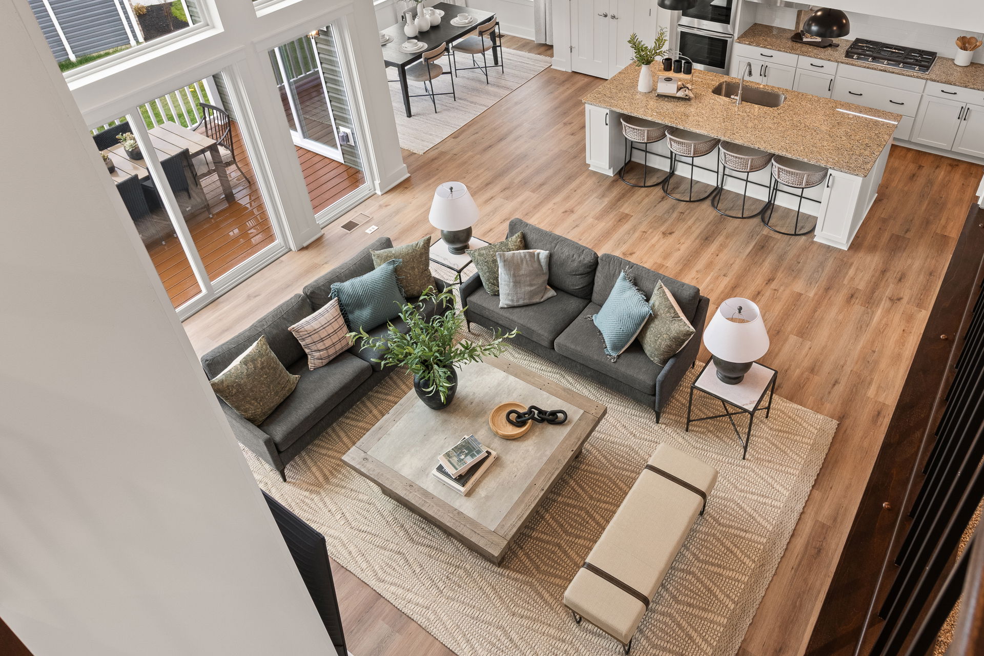 Modern open-concept living space with a gray sectional sofa, decorative pillows, and a wooden dining area, viewed from above.