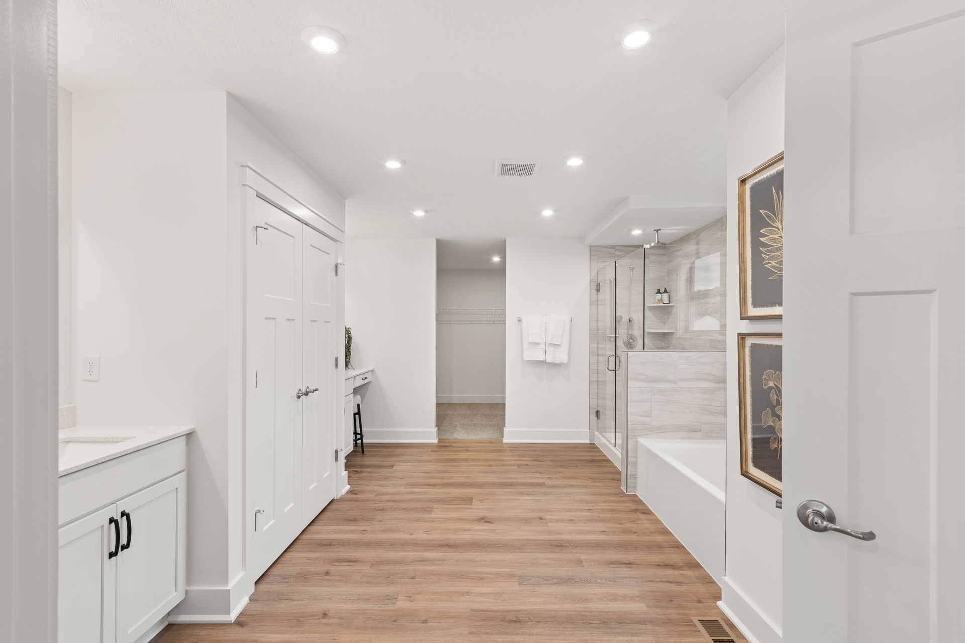 Modern bathroom with wood flooring, white cabinetry, double doors, and a glass-enclosed shower.