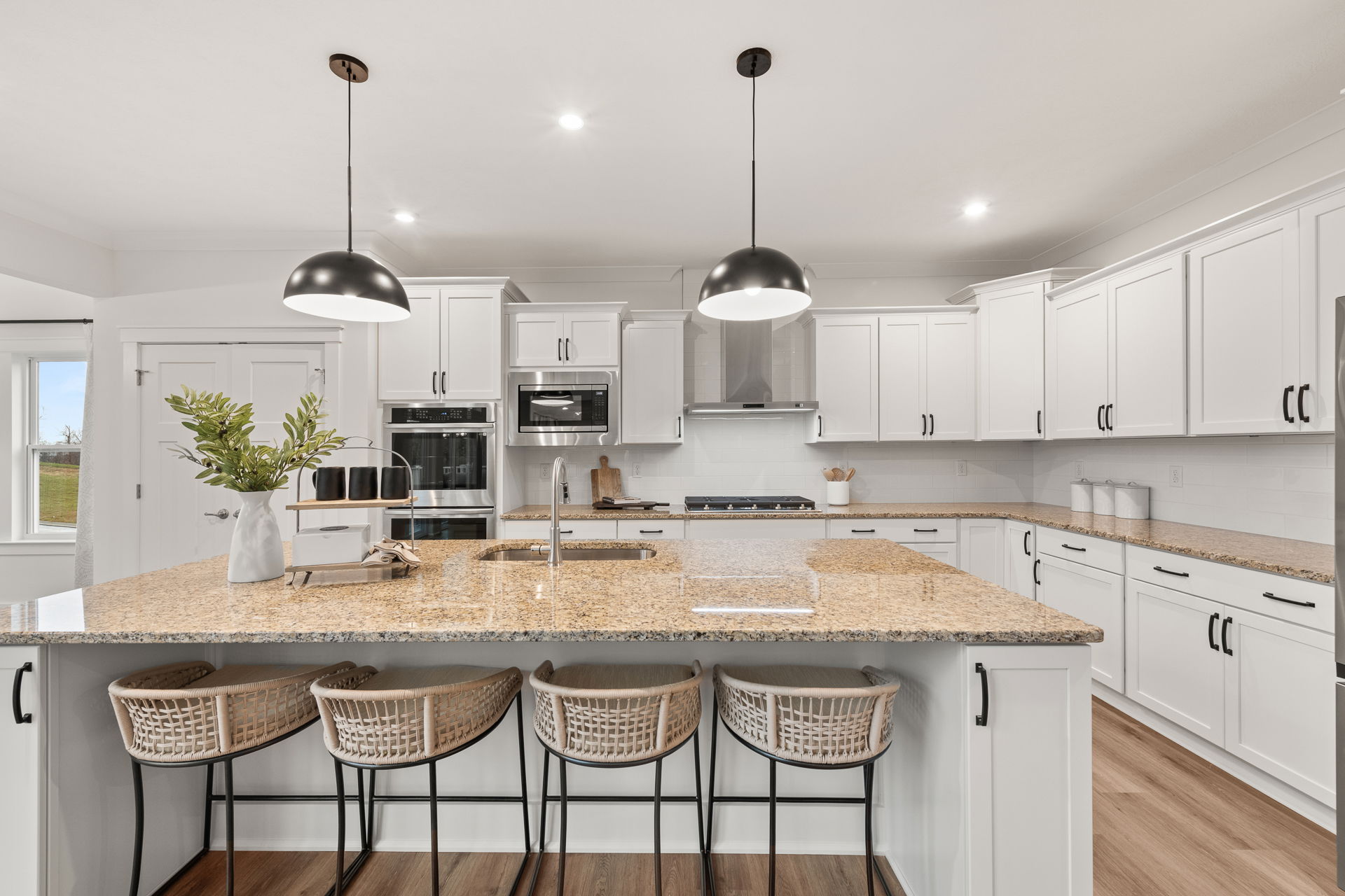 Modern kitchen with white cabinets, granite countertops, island seating, and pendant lighting.