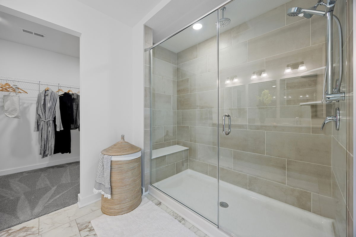 Luxurious modern bathroom with a spacious glass-enclosed shower and an adjacent walk-in closet.