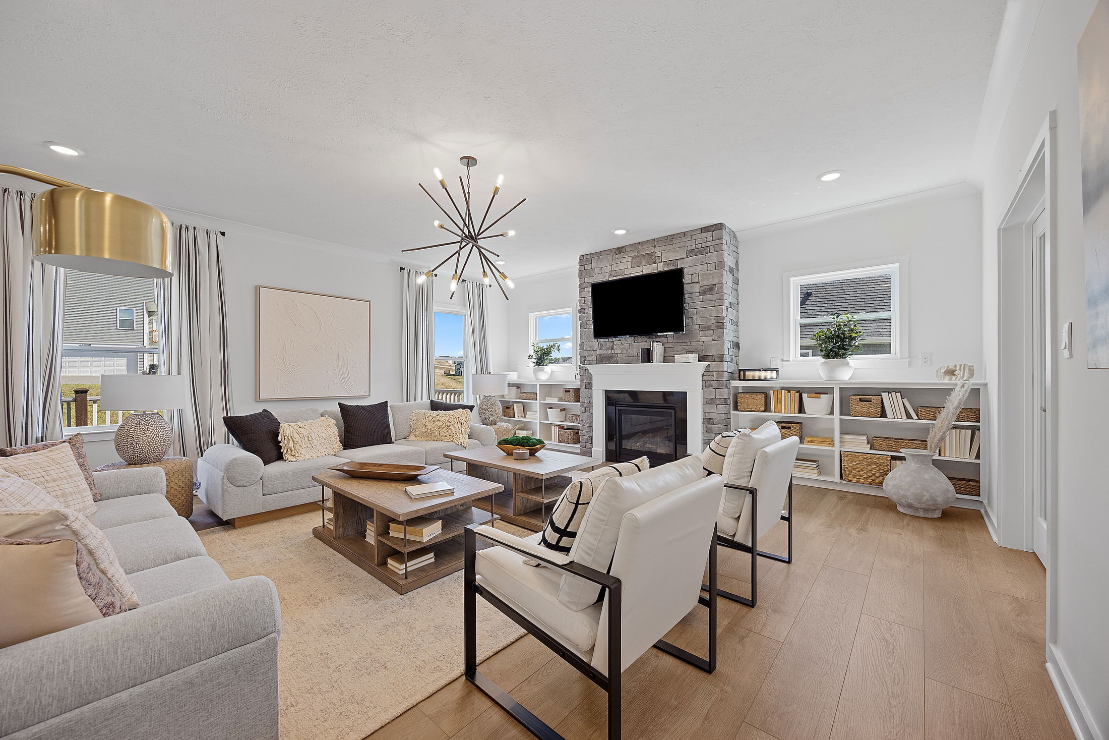 Modern living room with stylish furniture, stone fireplace, and contemporary lighting.