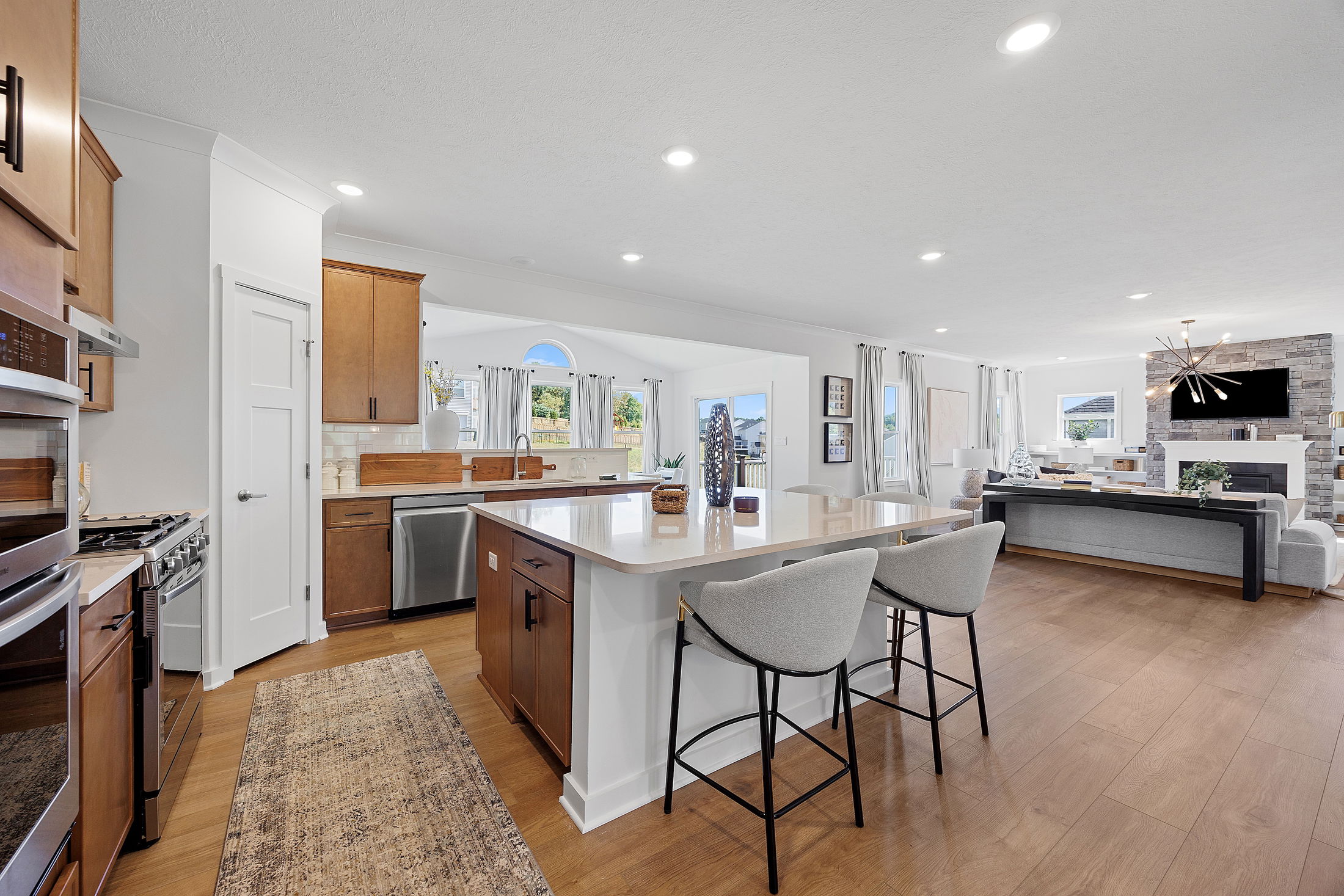 Modern open-concept kitchen and living room with wood flooring, sleek countertops, and contemporary furniture.
