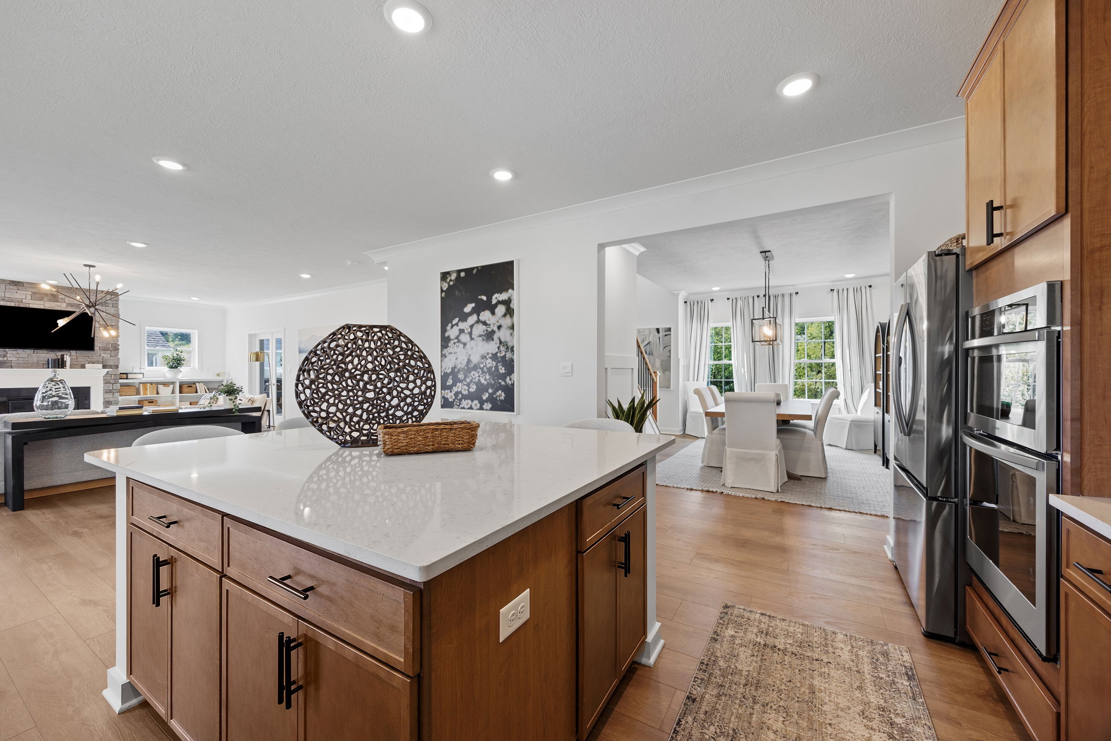 Modern open-concept kitchen and dining area with hardwood floors, featuring a large island, stainless steel appliances, and elegant decor.