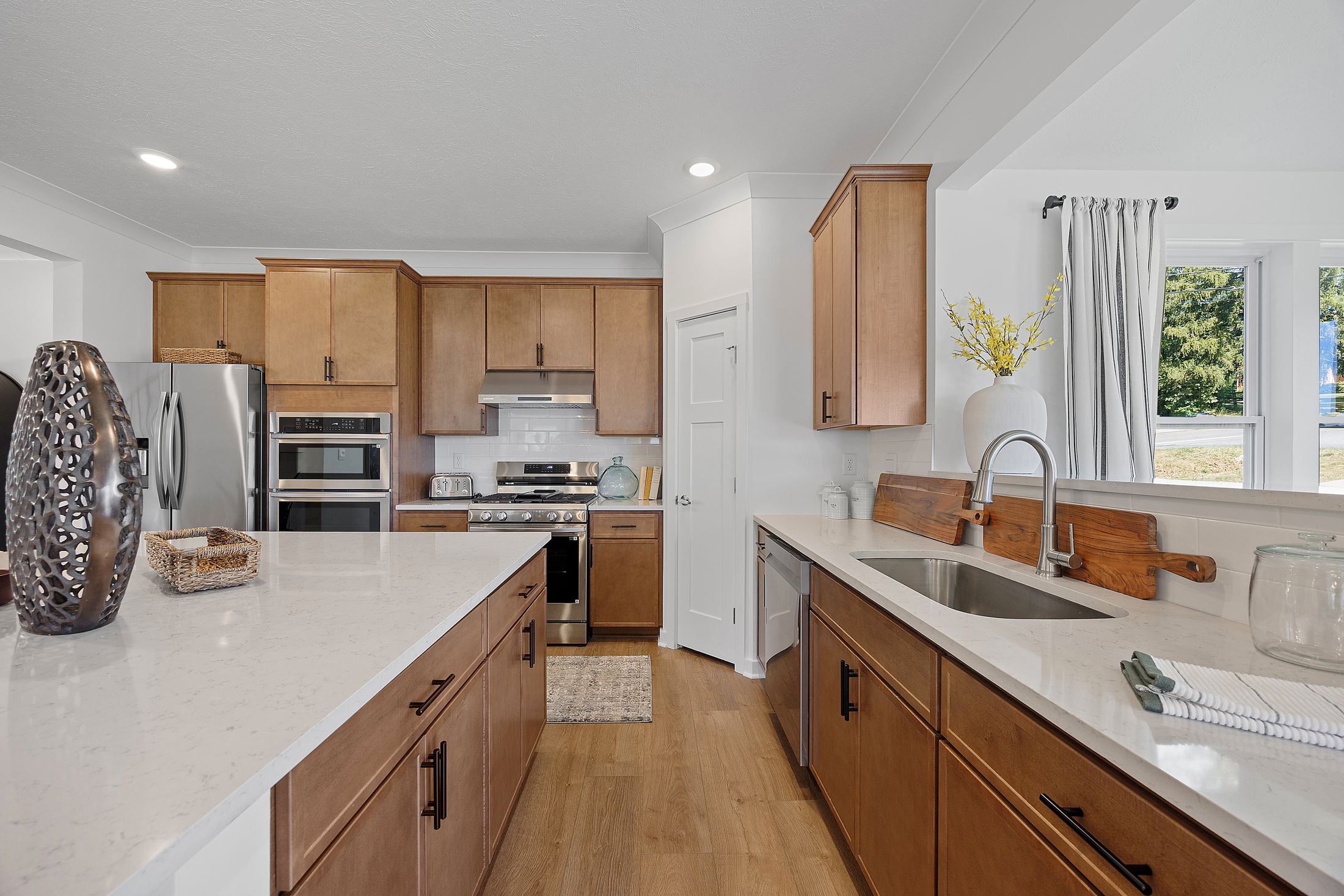 Modern kitchen with wooden cabinets, stainless steel appliances, and a large island featuring a decorative brown sculpture and woven basket.
