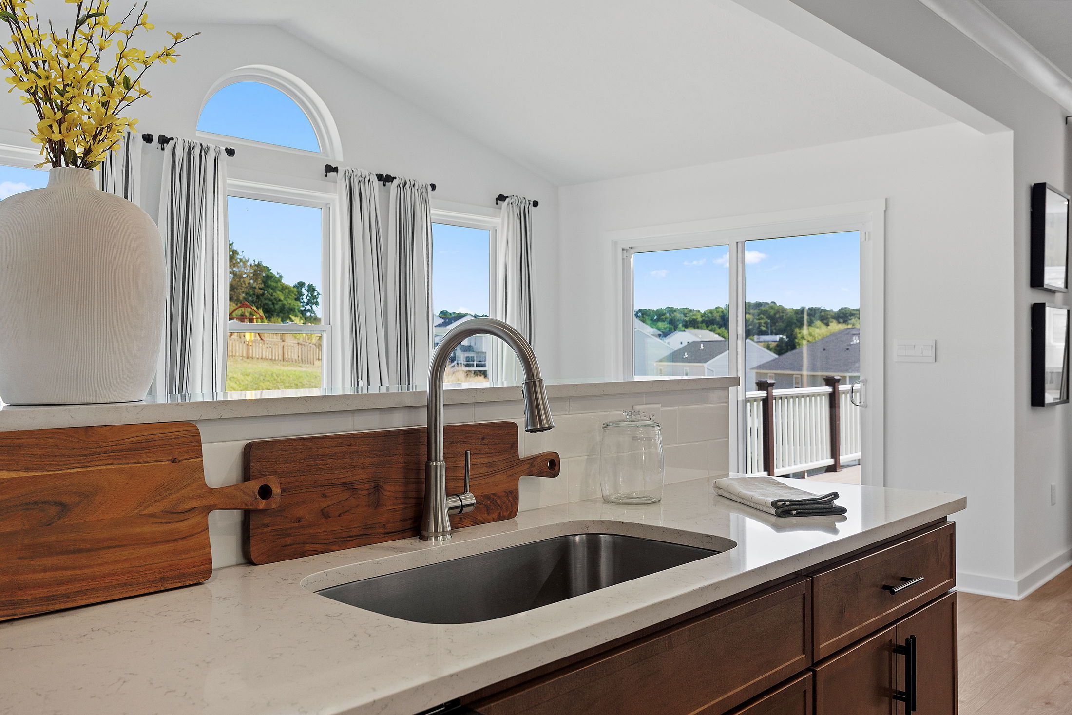 Modern kitchen with a stainless steel sink, wooden cabinetry, and large windows offering natural light and scenic views.