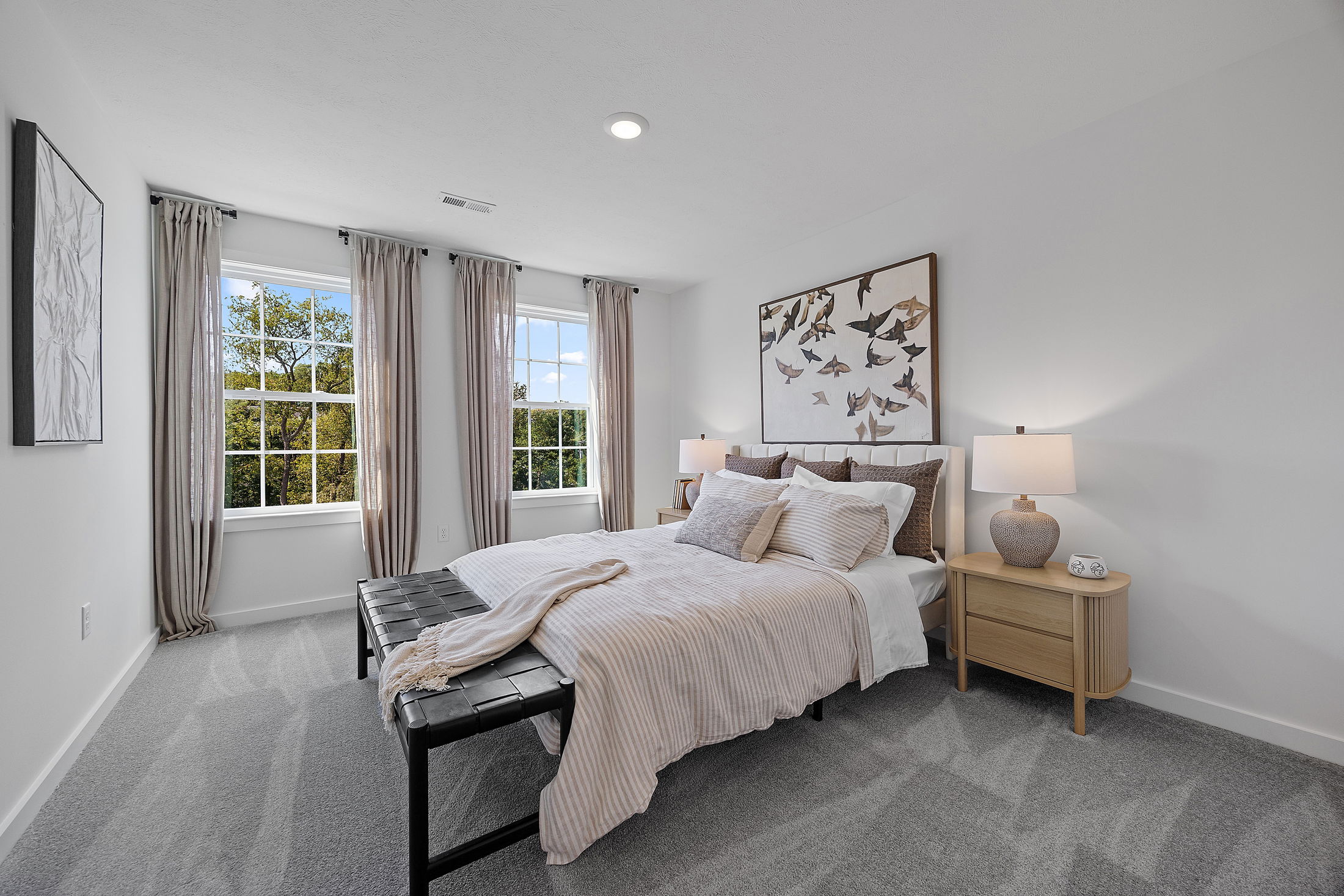 Modern, bright bedroom with neutral decor, large windows, and stylish furnishings.
