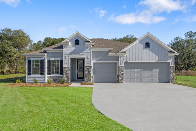 Modern suburban home with a well-maintained lawn, gray siding, and a two-car garage under a clear blue sky.