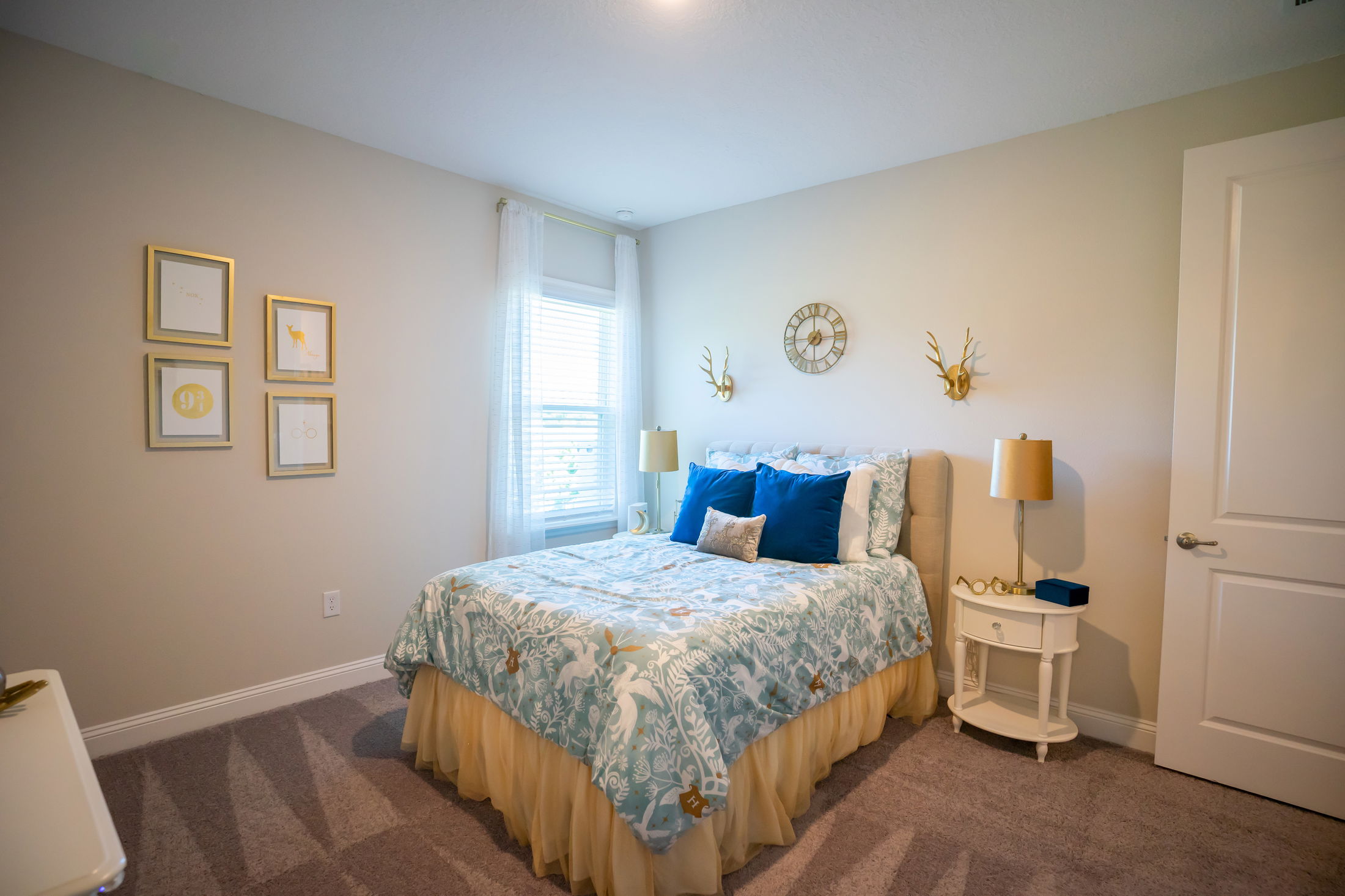 Cozy bedroom with a stylish bed featuring blue and white bedding, decorative pillows, gold accents, and elegant wall art.
