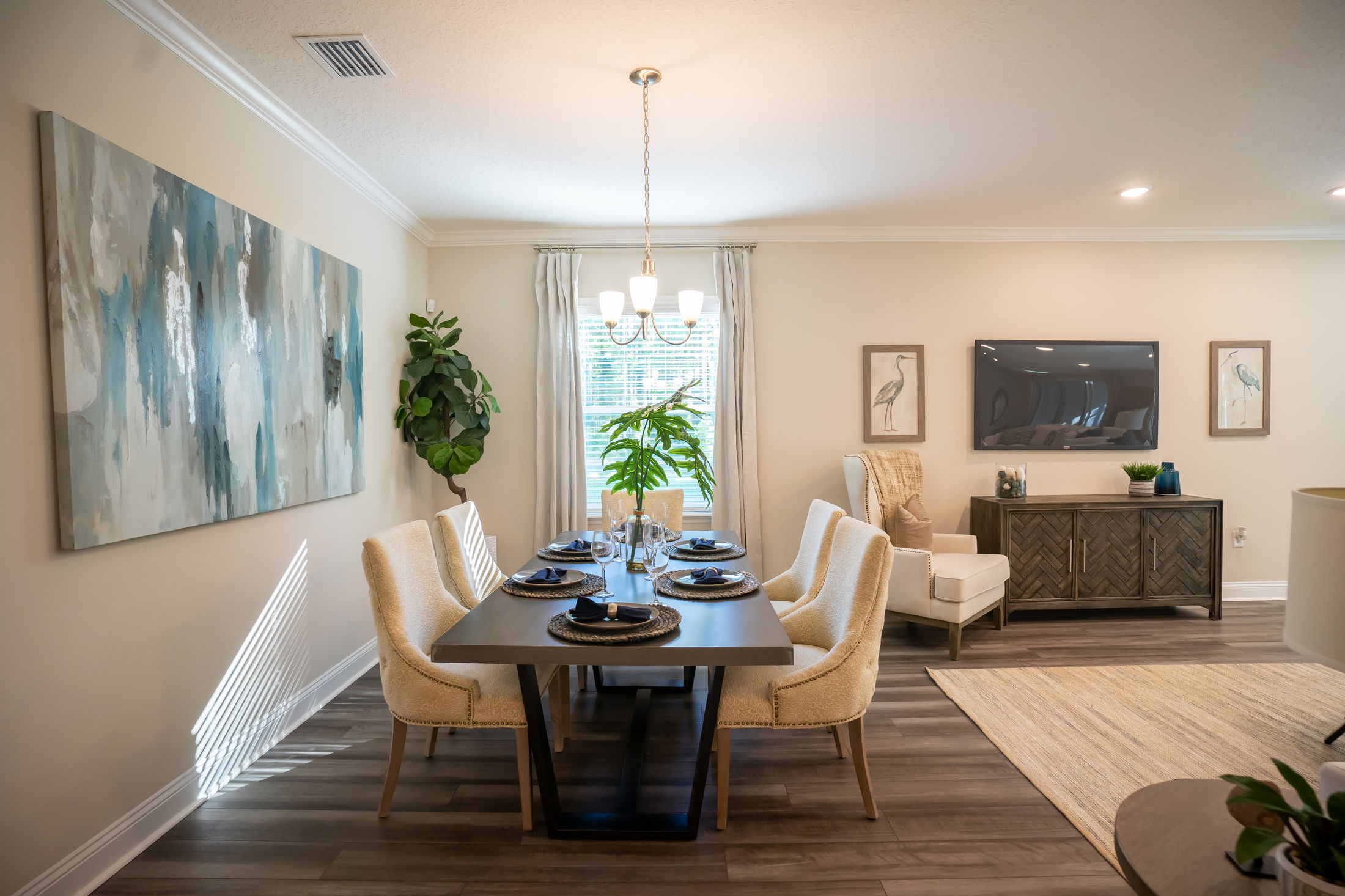 Elegant modern dining room featuring a stylish table setting, large abstract wall art, and natural light streaming in.