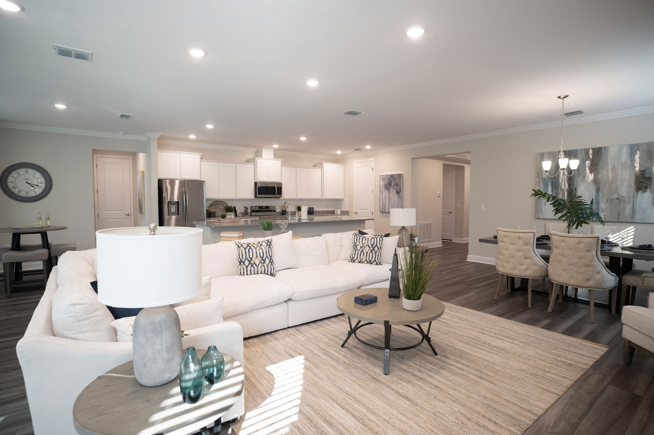 Modern open-concept living room and kitchen with white sofas, elegant decor, and a dining area in a contemporary home.