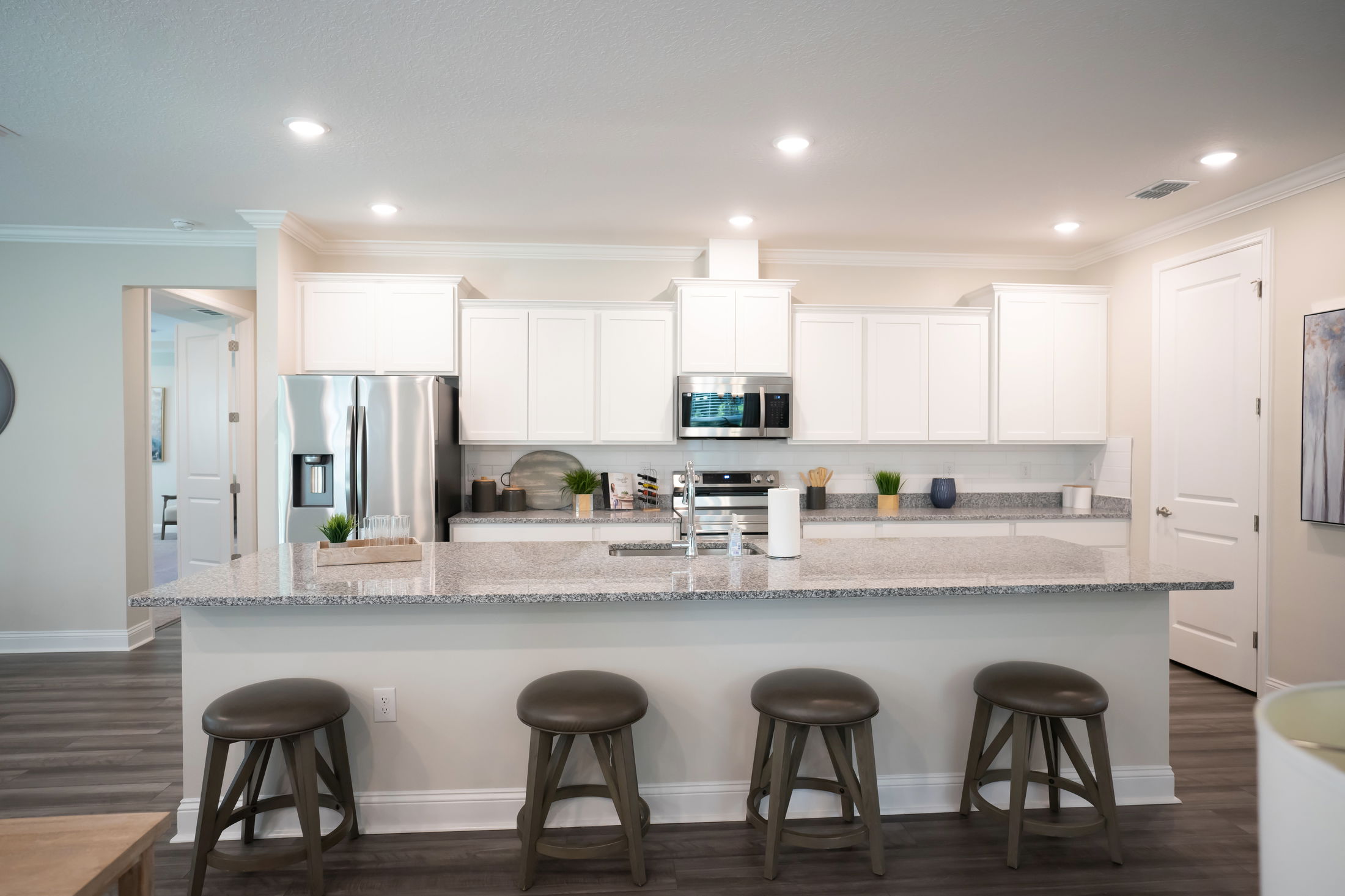 Modern kitchen interior with white cabinets, stainless steel appliances, and granite countertops featuring bar stools.