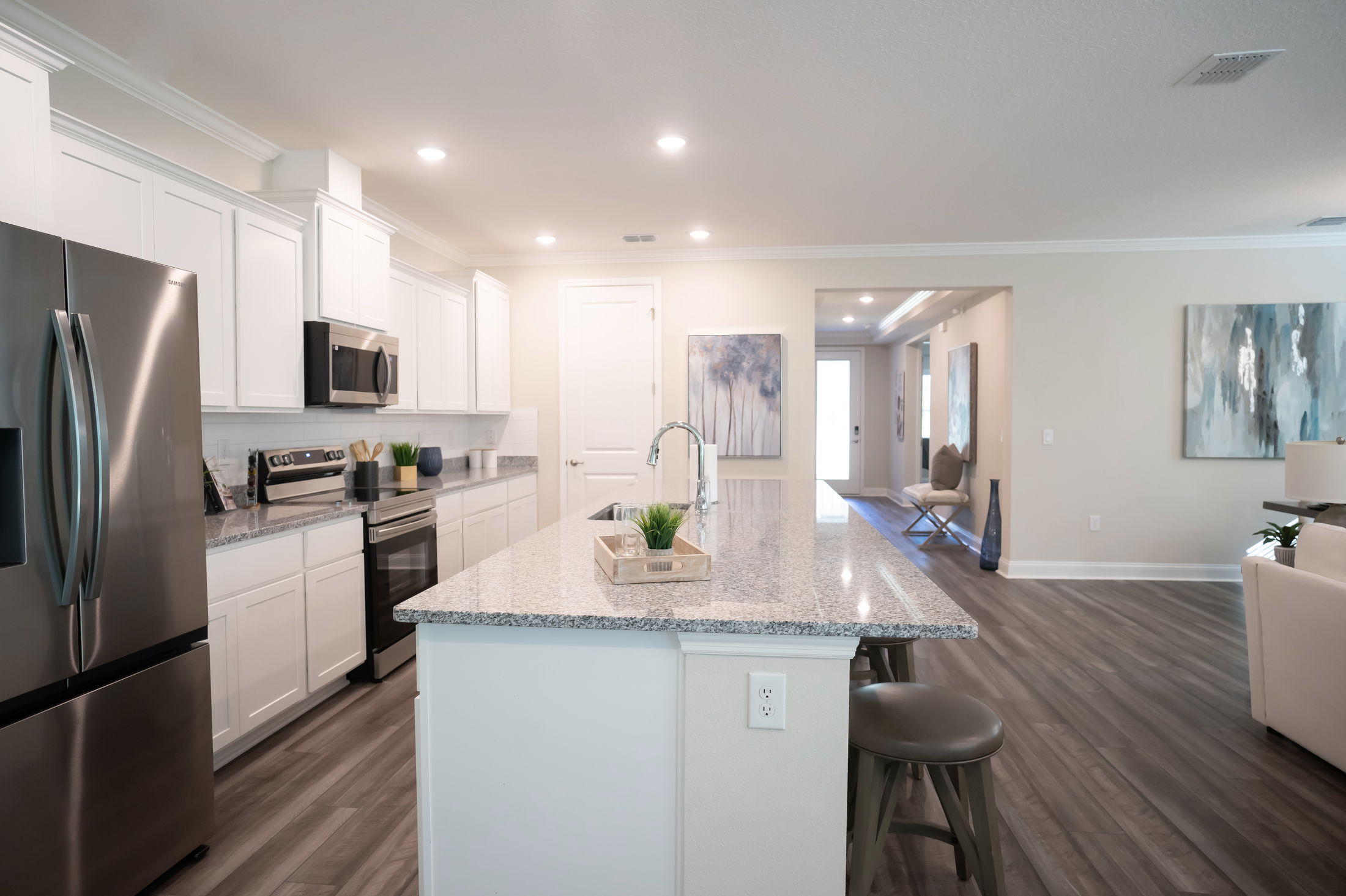 Modern kitchen interior with white cabinets, stainless steel appliances, and a granite countertop island.