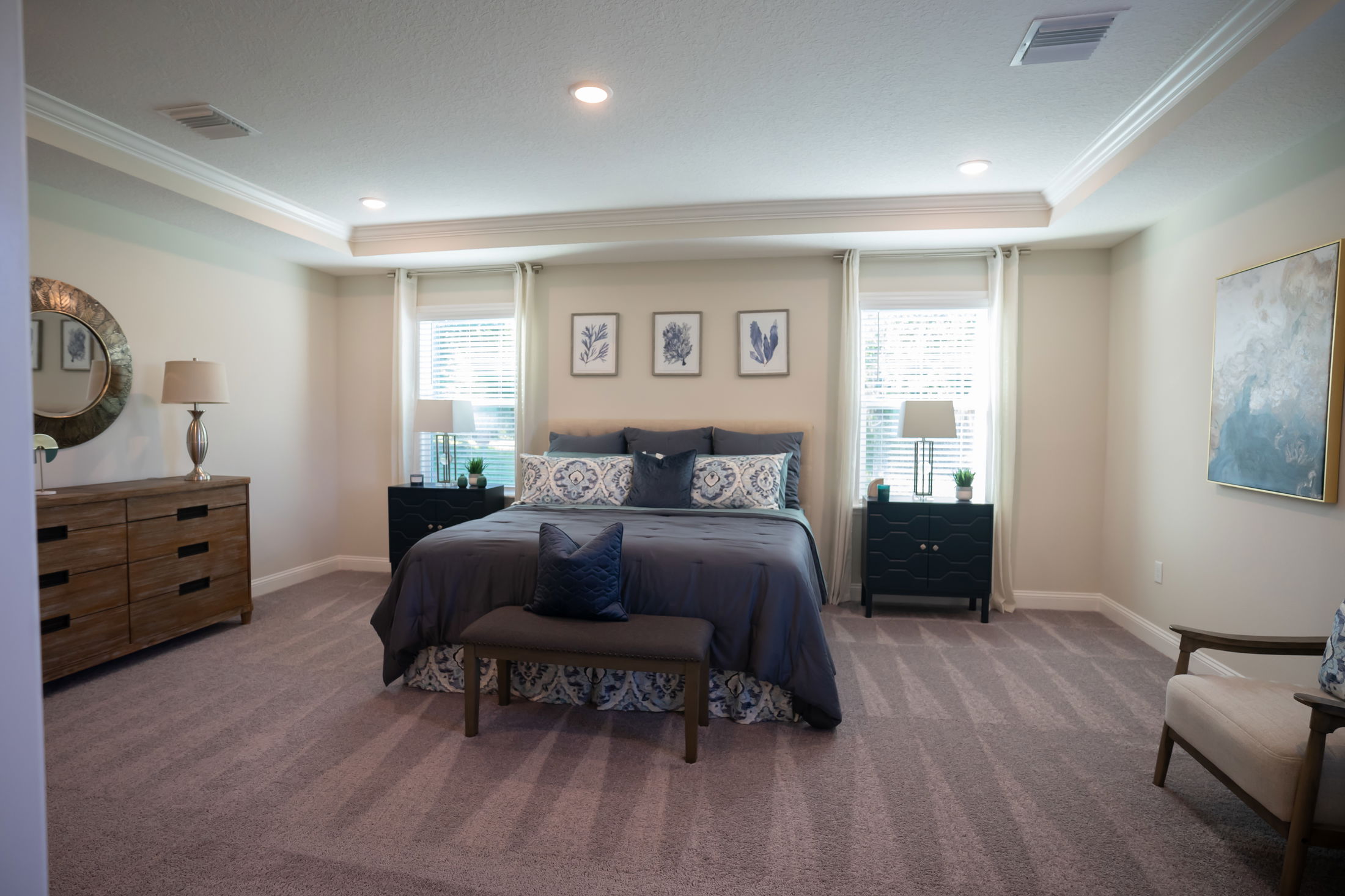Spacious modern bedroom with a large bed, stylish decor, and natural lighting from two windows.