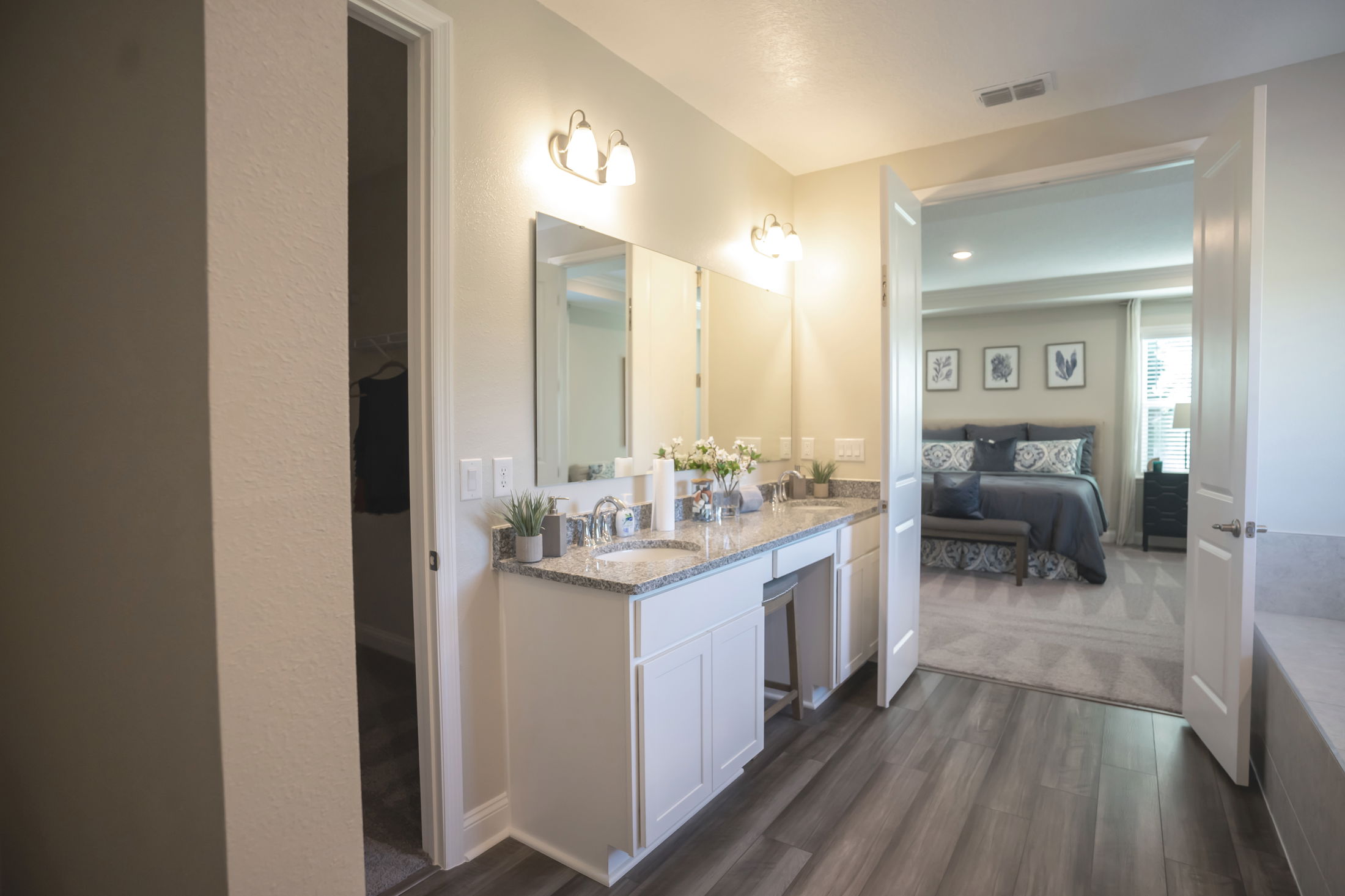 Modern bathroom with granite countertop and dual sinks leading to a stylish bedroom in a contemporary home.