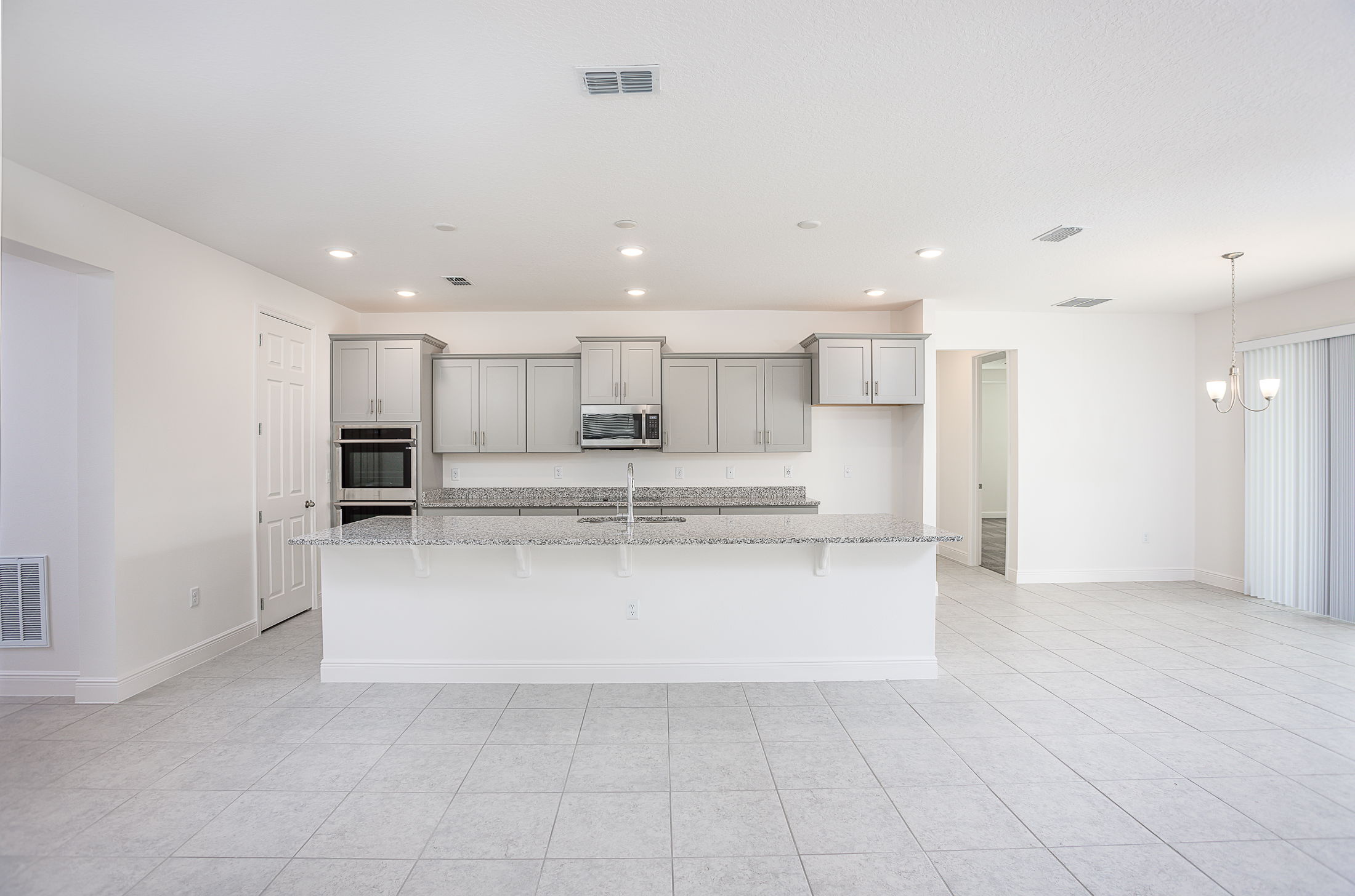 Modern kitchen with light gray cabinets, granite countertops, and a spacious island in a bright, open floor plan.