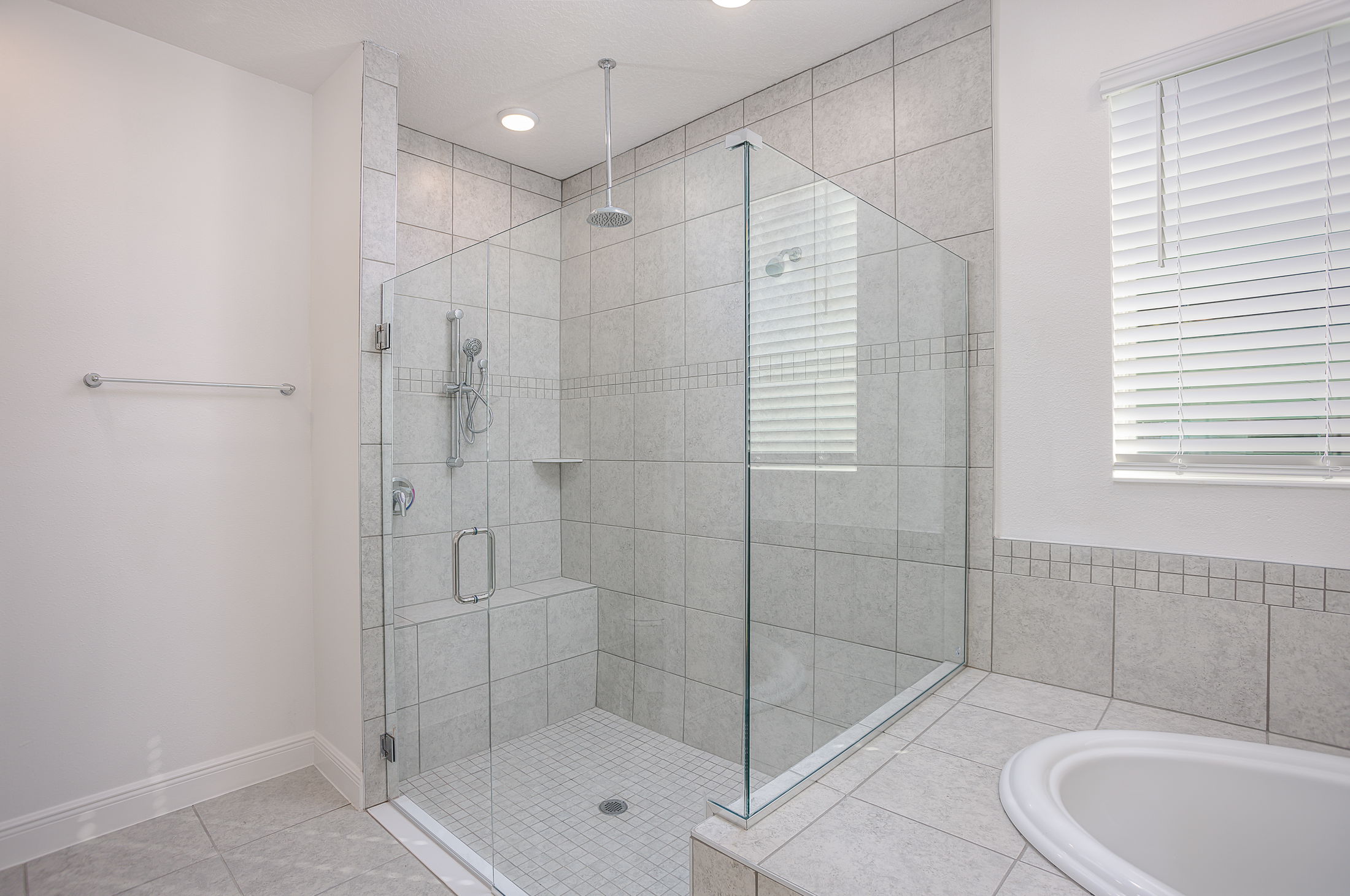 Modern bathroom with a spacious glass-enclosed shower and tiled walls.