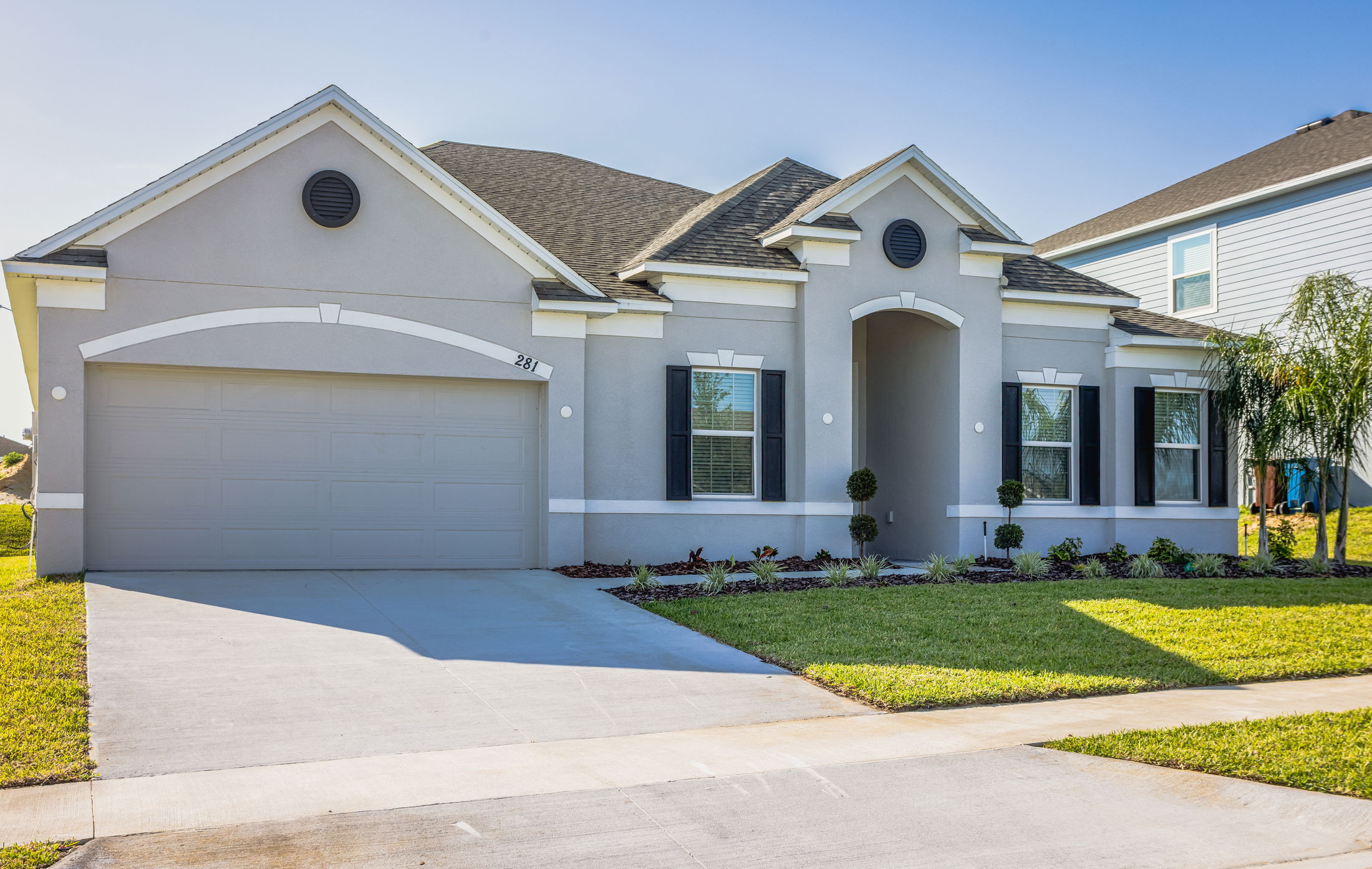 Modern single-story gray house with garage and manicured lawn.