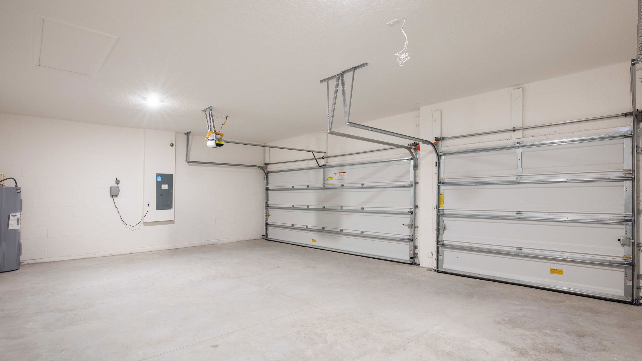 Empty two-car garage with white walls, concrete floor, and overhead lighting.