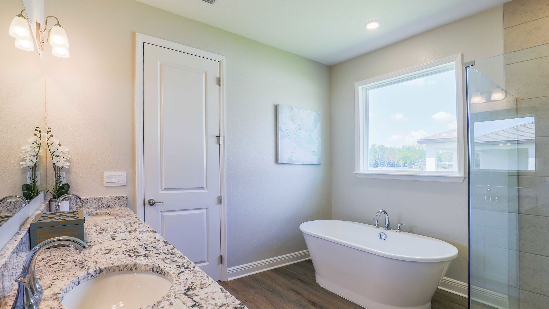 Modern bathroom with a freestanding tub, granite countertops, and large window for natural light.