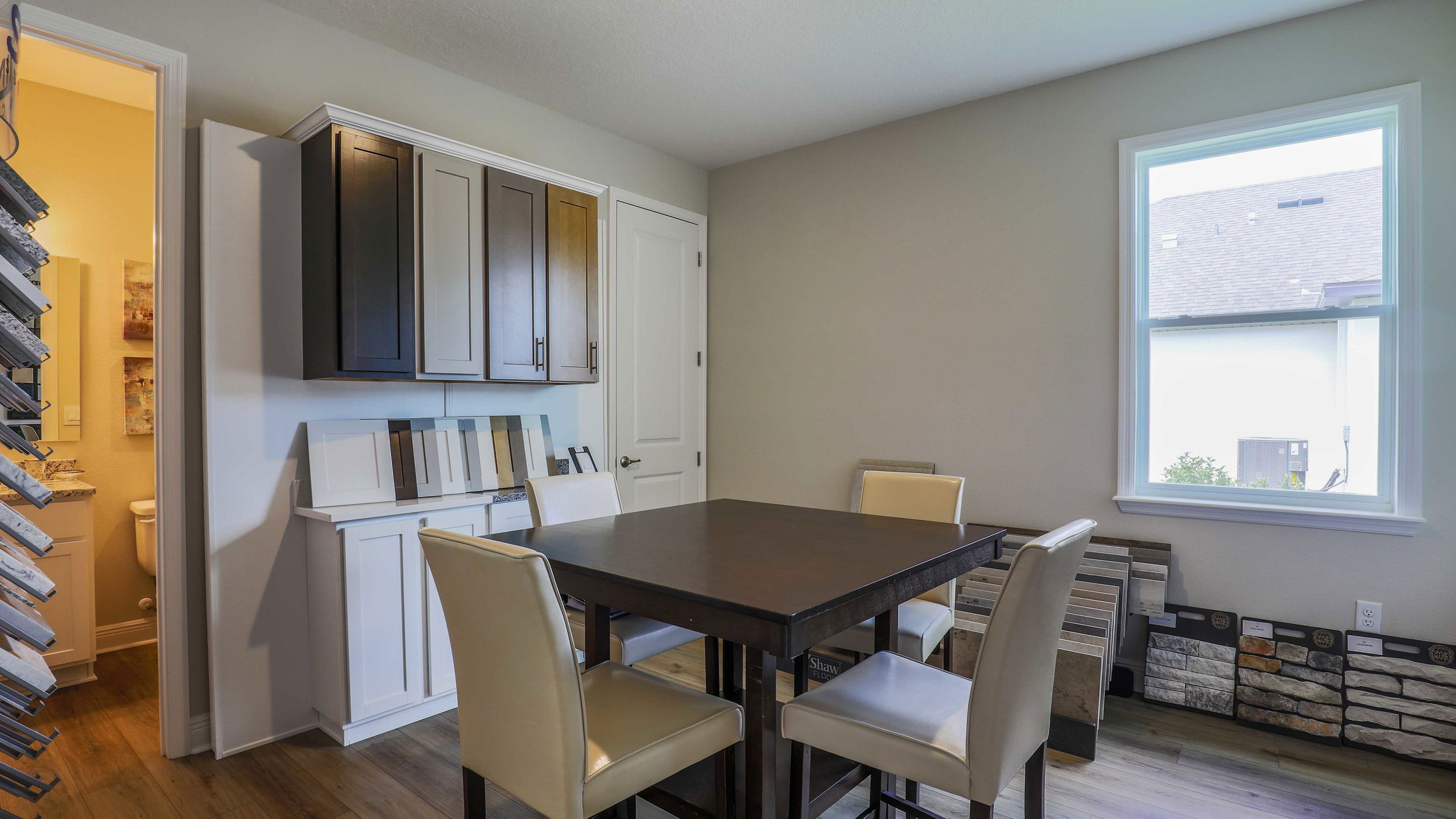 Modern design consultation room with a table, chairs, and various countertop and stone veneer samples displayed against the walls.