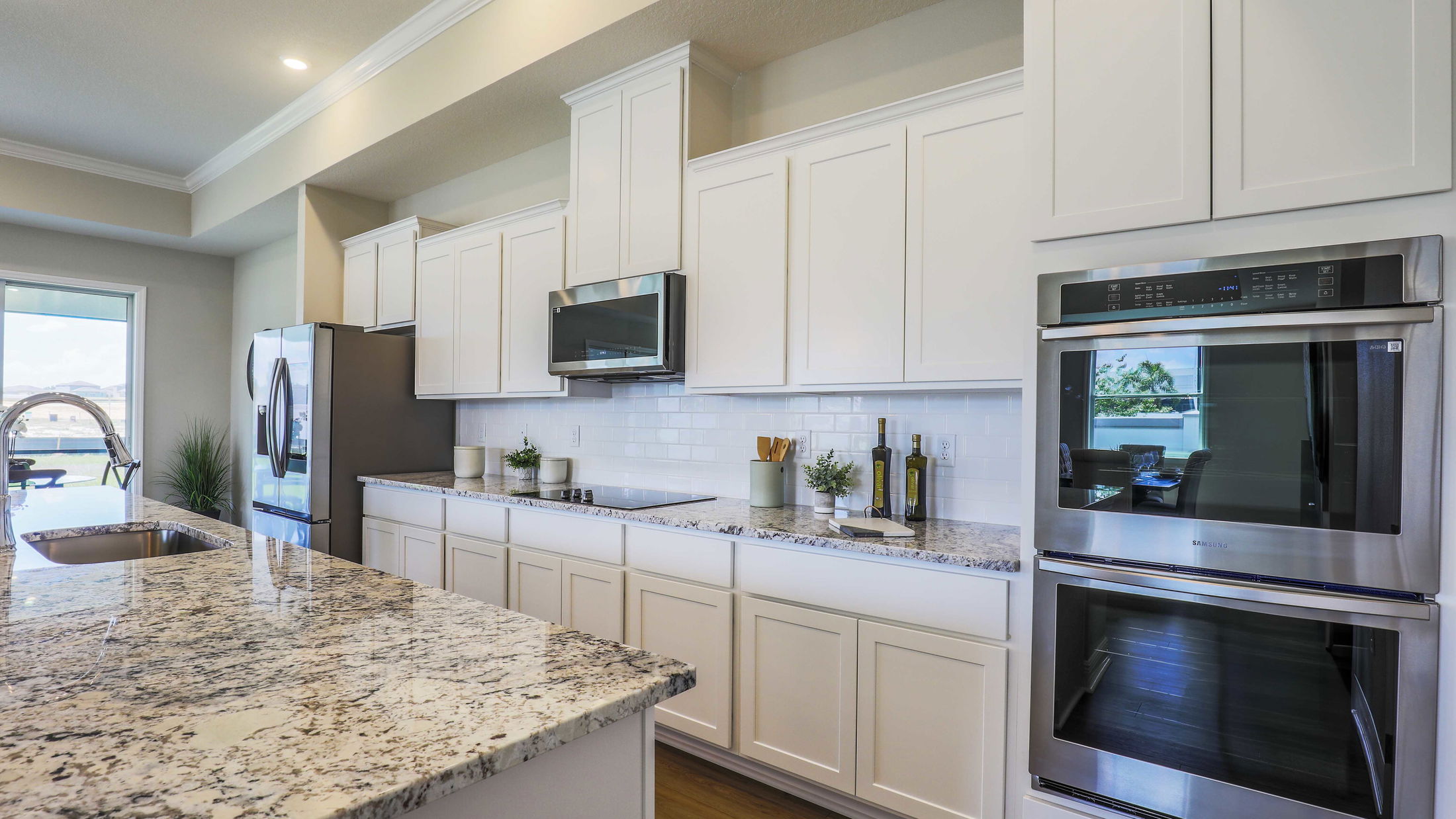 Modern kitchen with white cabinets, granite countertops, stainless steel appliances, and natural lighting.