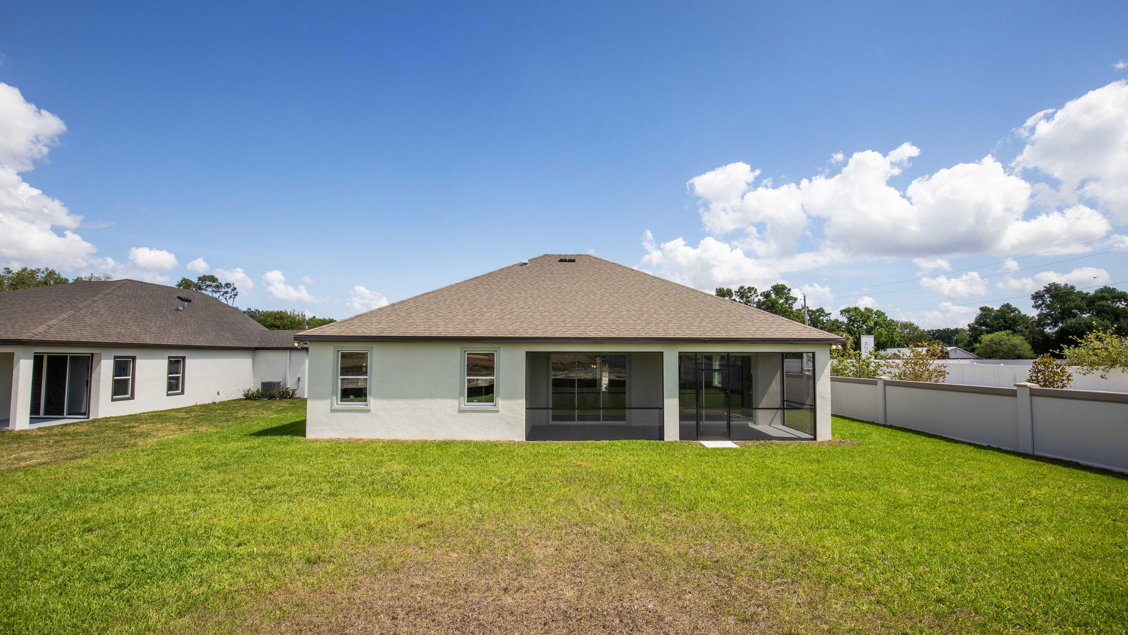 Rear view of a modern suburban house with a spacious backyard and clear blue sky.