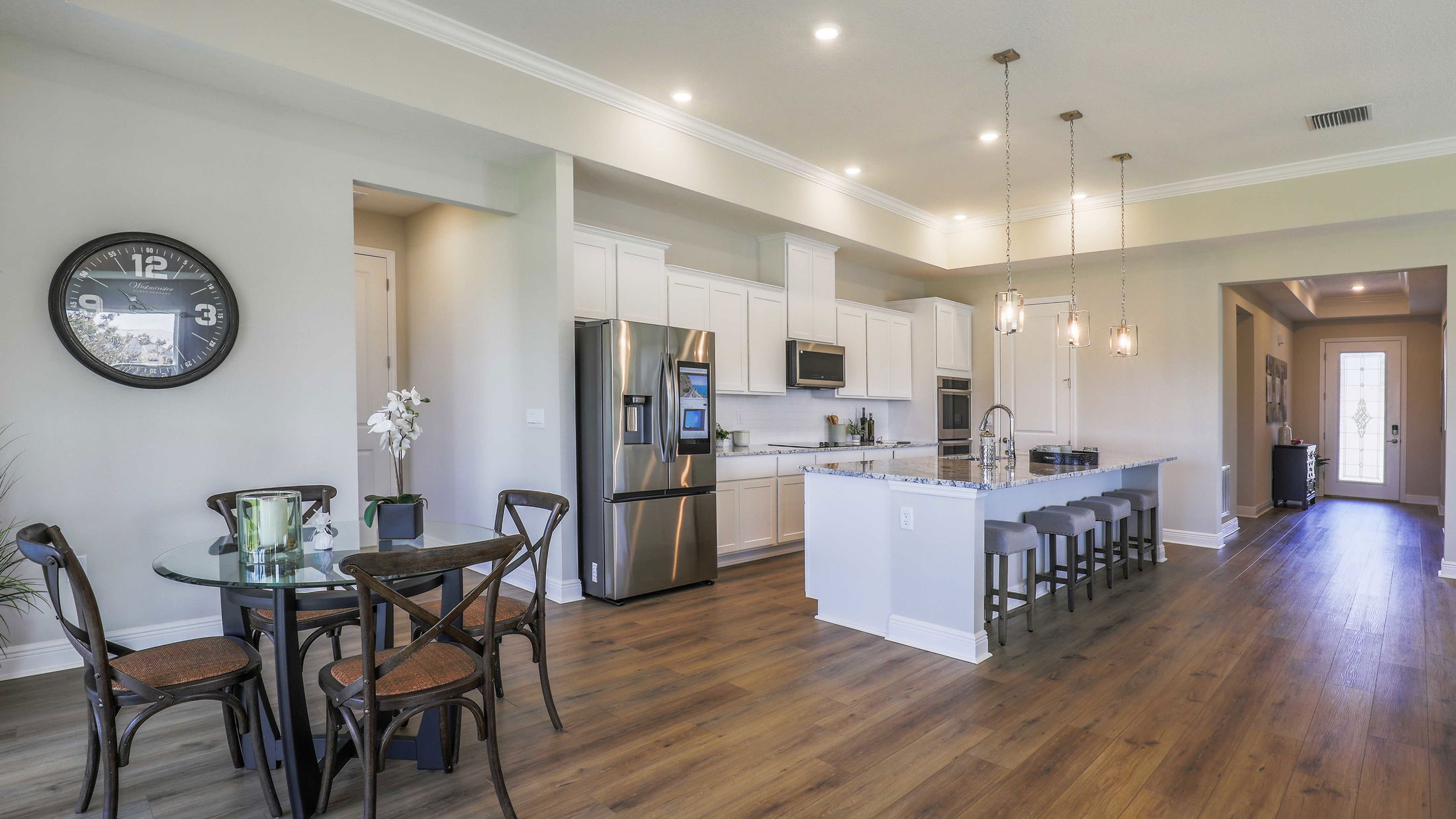 Modern kitchen and dining area with white cabinets, stainless steel appliances, and pendant lighting.