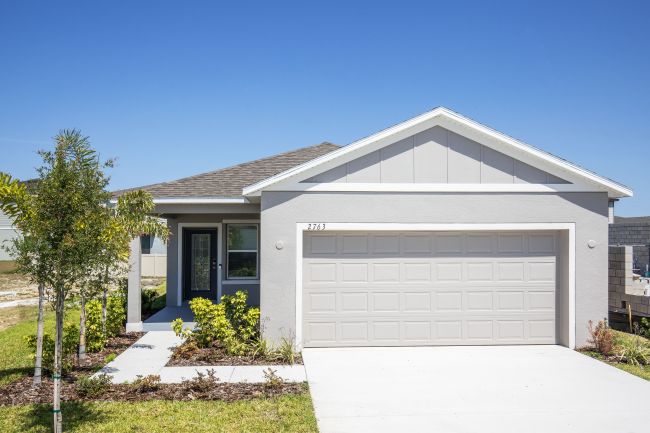 Modern single-story house with a two-car garage and well-maintained front yard under a clear blue sky.