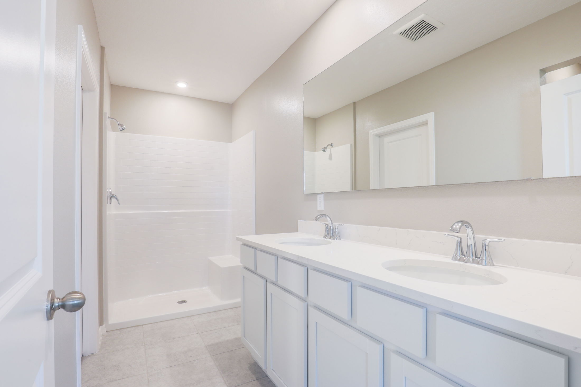 Modern bathroom with dual sinks, large mirror, and a spacious walk-in shower.