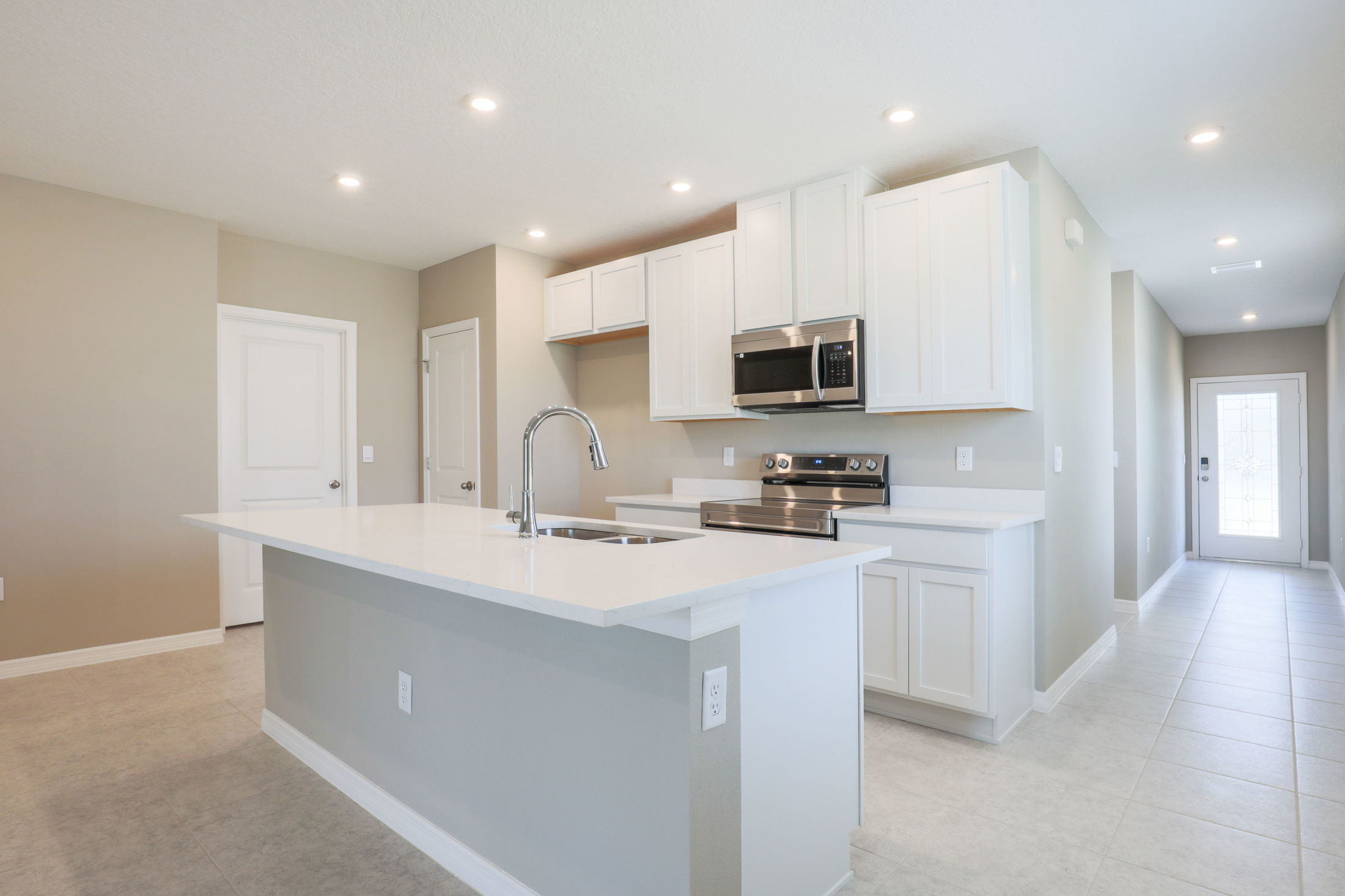 Modern kitchen interior with white cabinets, island sink, and stainless steel appliances in a bright, spacious layout.