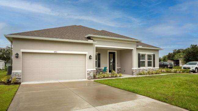 Modern single-story house with a two-car garage, stone accents, and landscaped front yard under a clear blue sky.