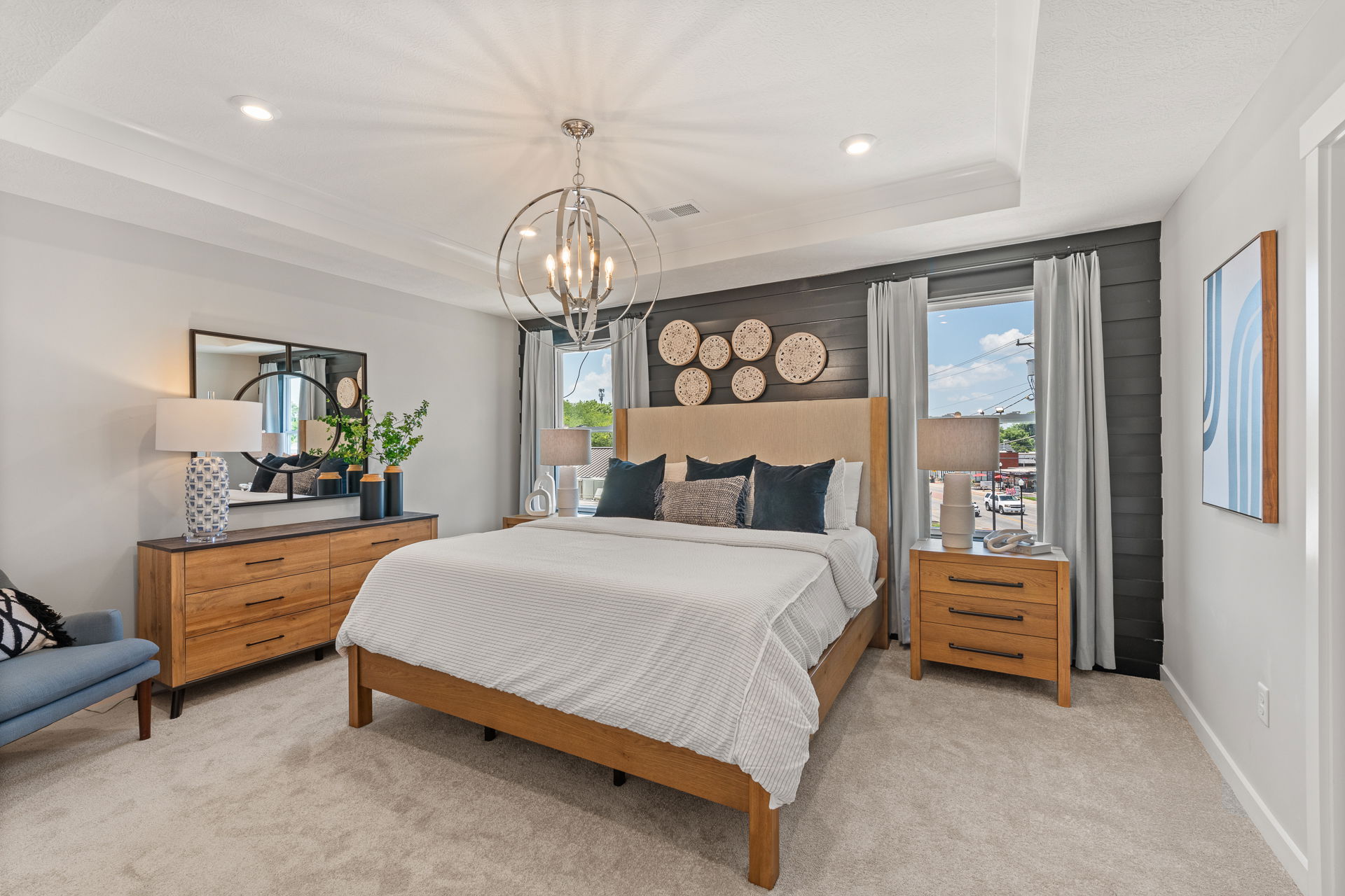 Modern bedroom interior with stylish wooden furniture, patterned decor, and a chandelier, featuring a cozy bed with decorative pillows.