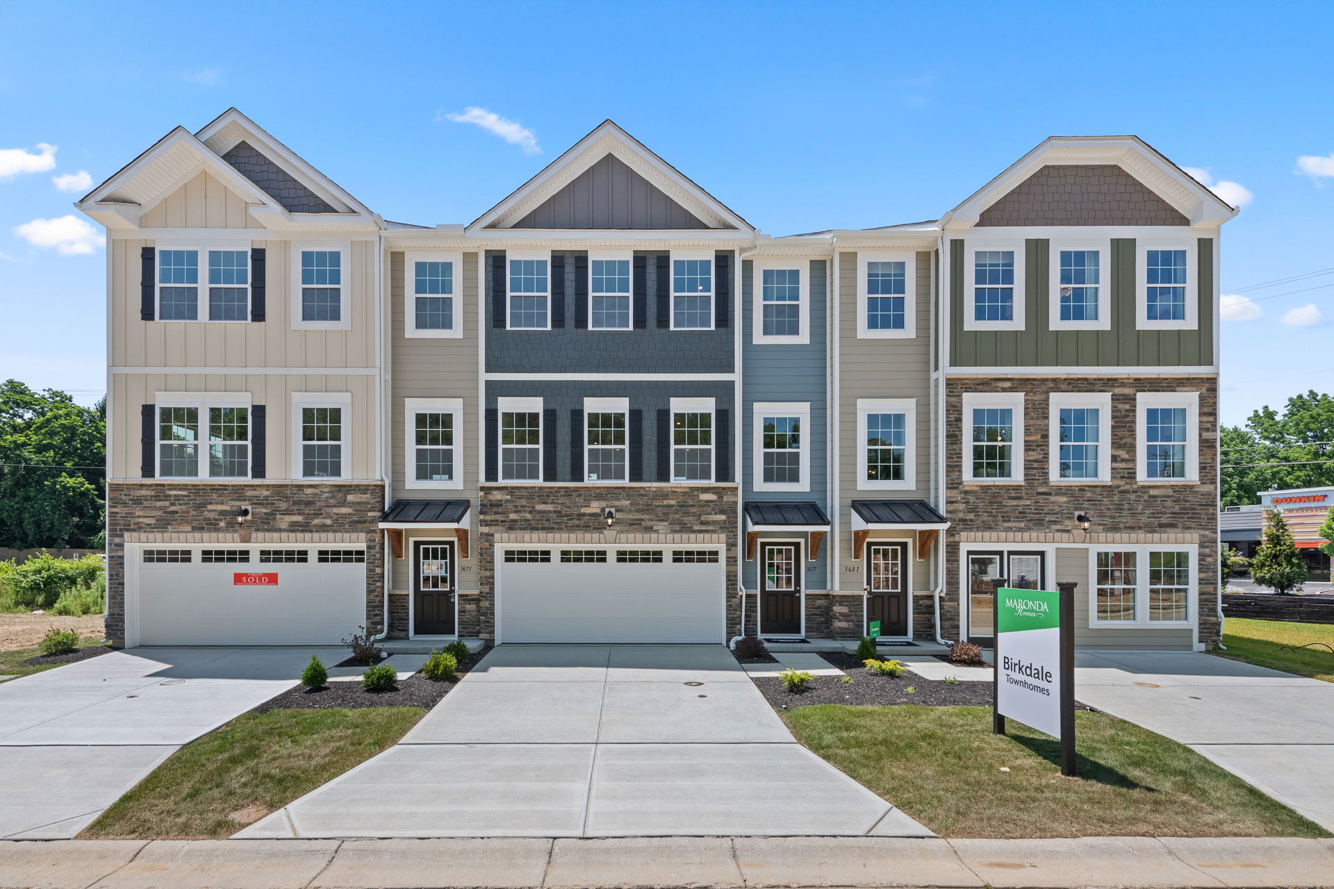 Modern three-story townhouses at Birkdale Townhomes with stone accents and neatly manicured lawns.