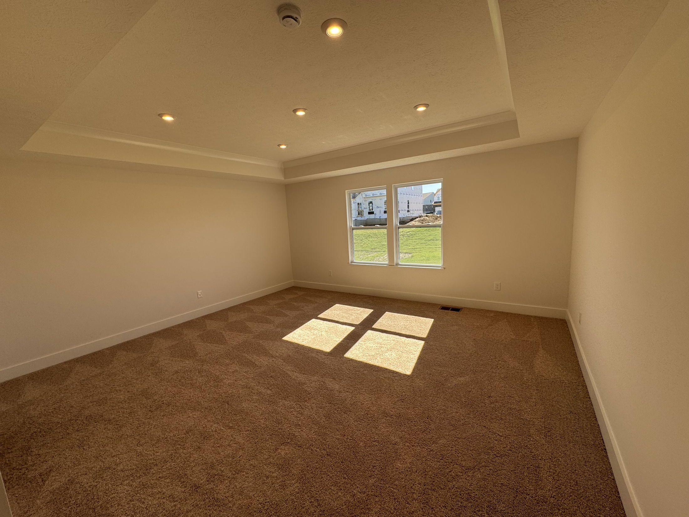 Bright and spacious empty room with large windows and plush carpet, perfect for home staging or real estate listings.