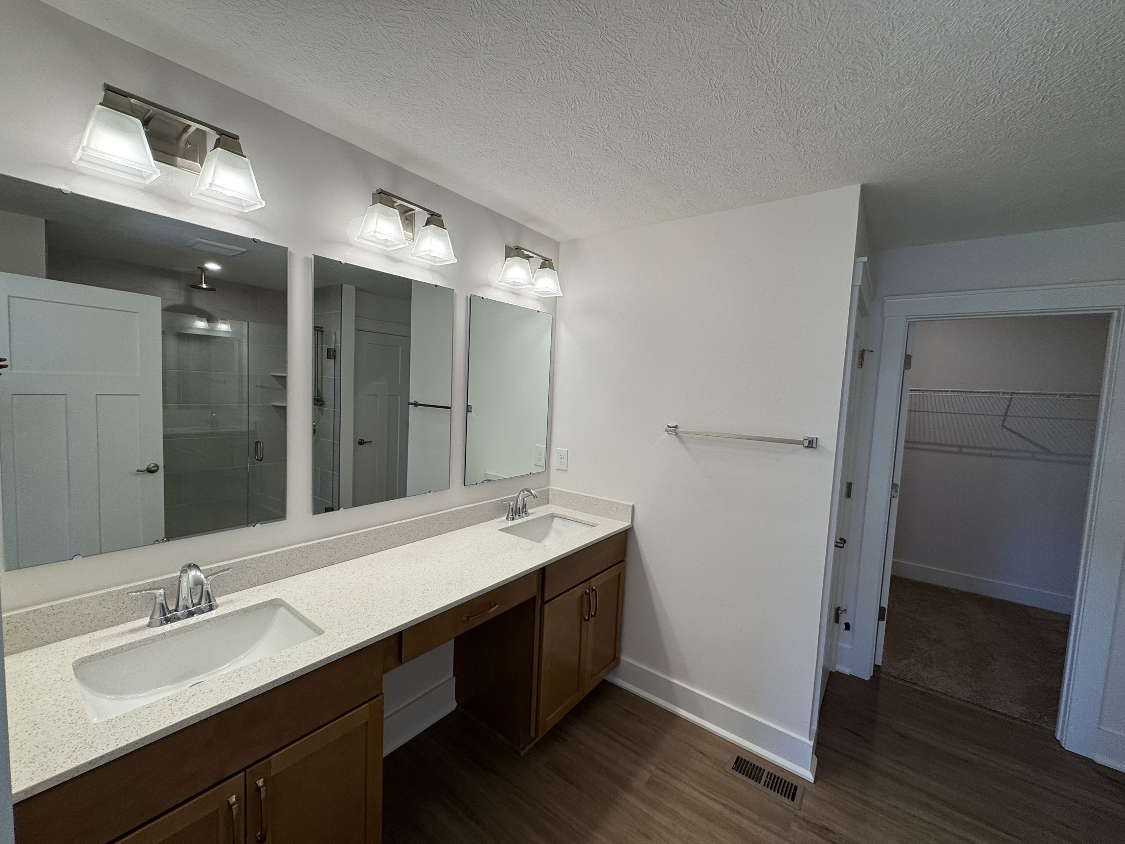 Modern bathroom featuring double sinks, a lighted mirror, and a spacious closet.
