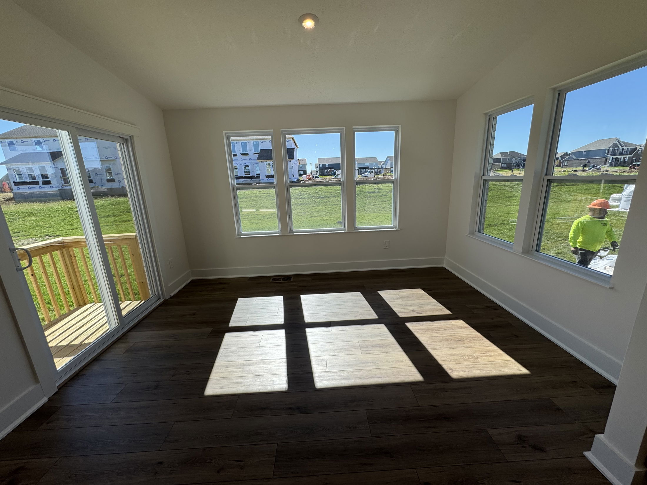 Bright, modern sunroom with large windows and wood flooring, open to a backyard view.