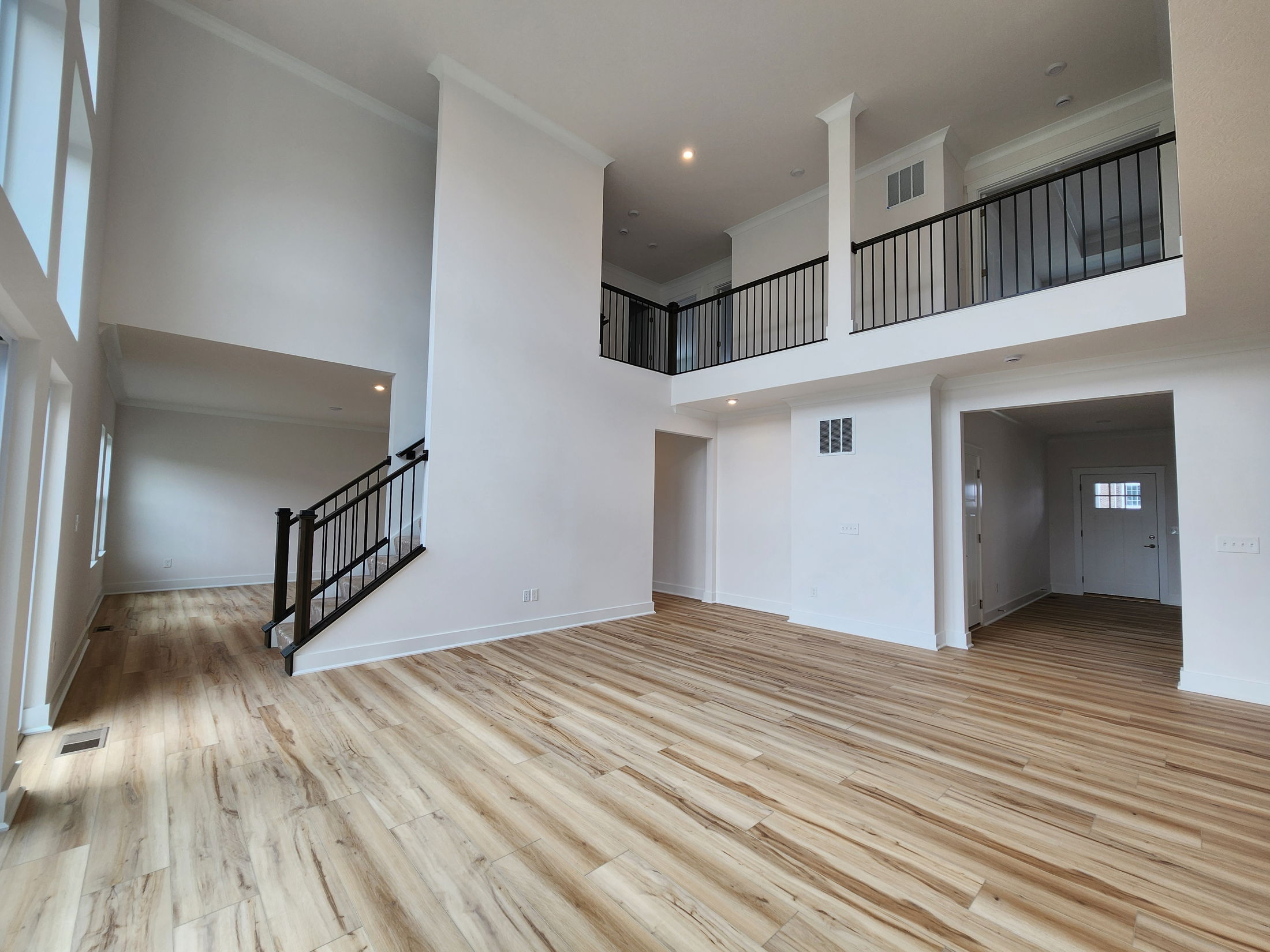 Spacious modern interior with high ceilings, wood flooring, and an open balcony in a contemporary home.