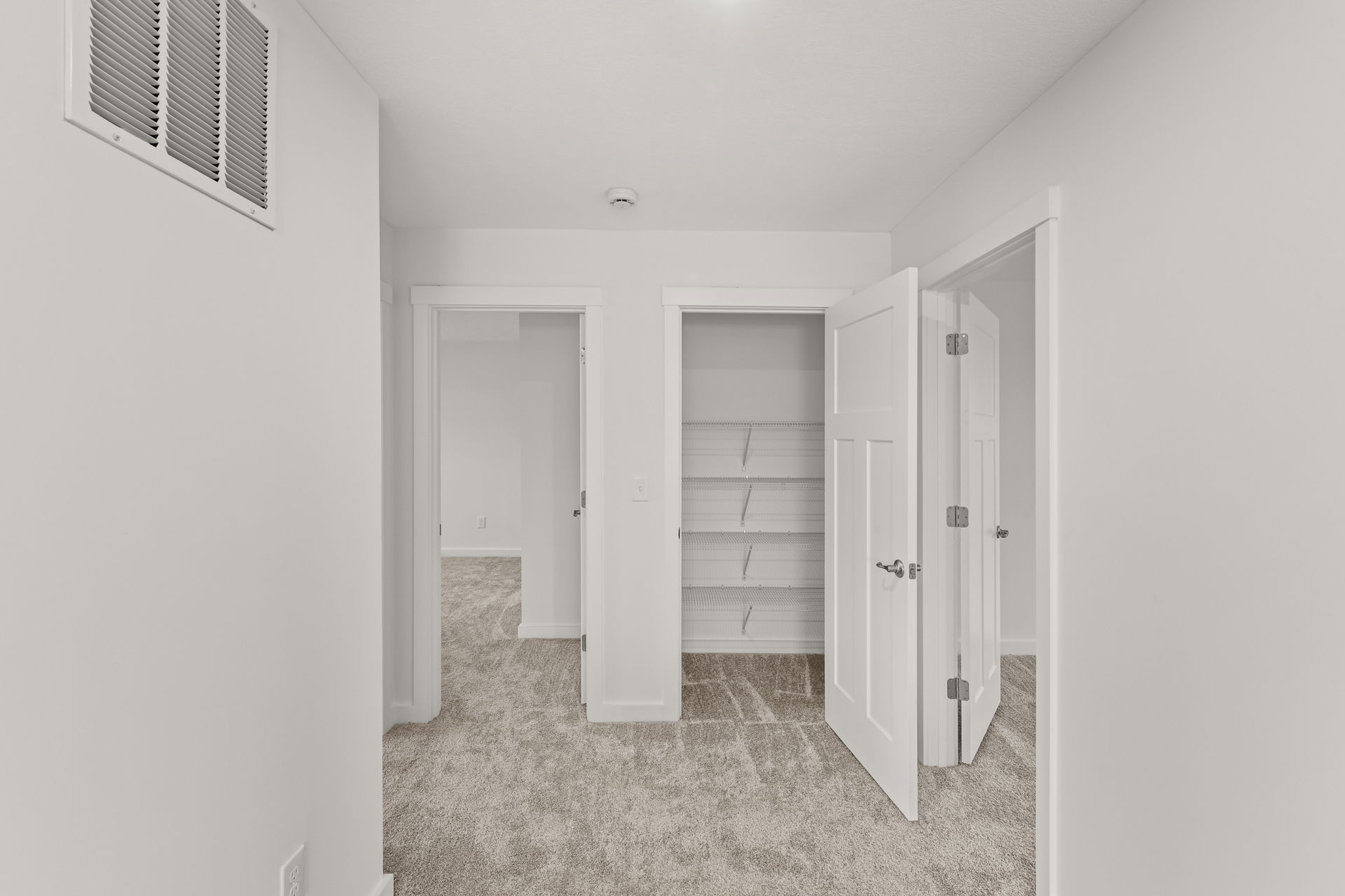 Modern white interior room with open closet doors and carpet flooring.