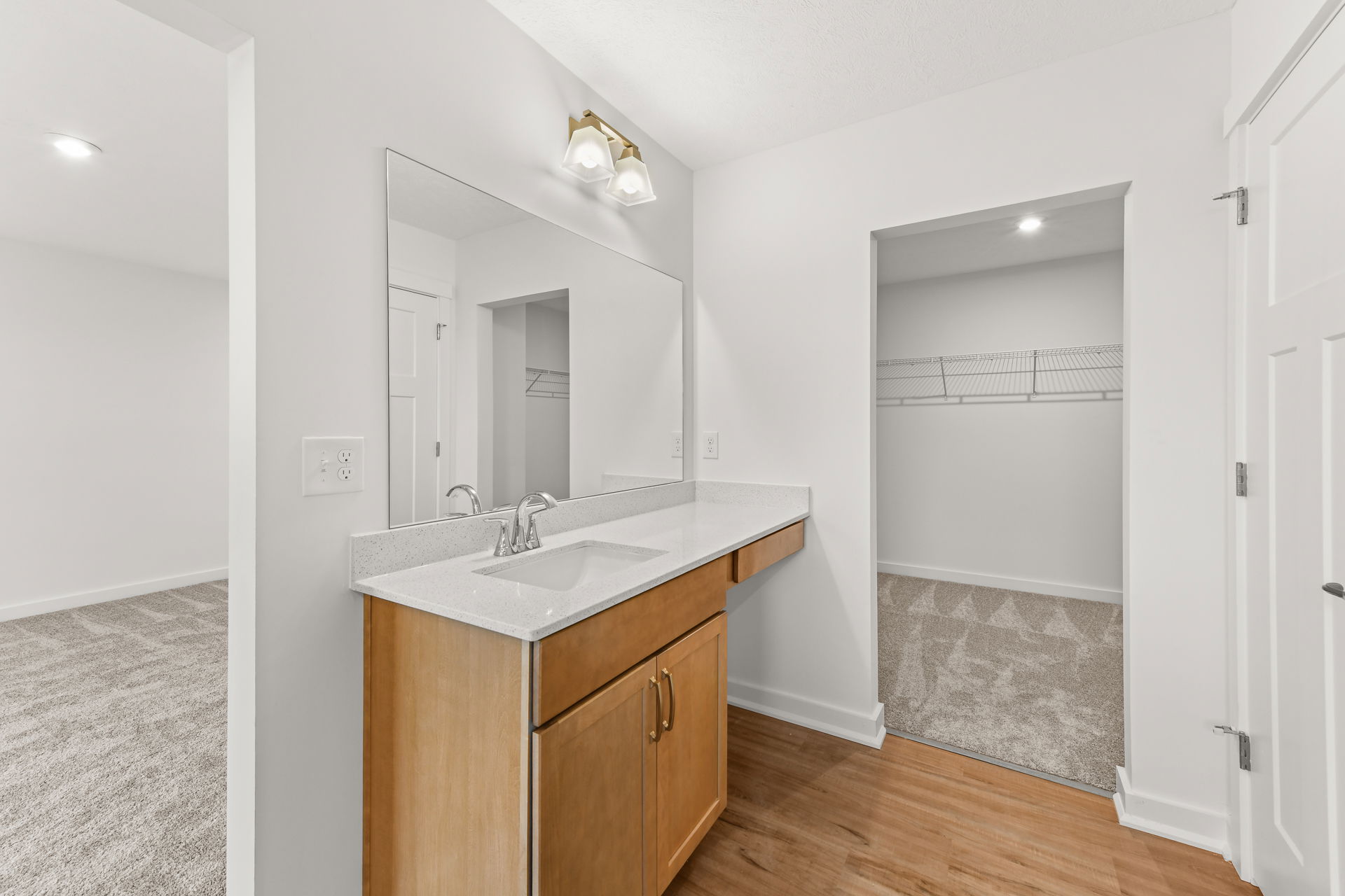 Modern bathroom vanity with wooden cabinet and large mirror in a bright interior space.