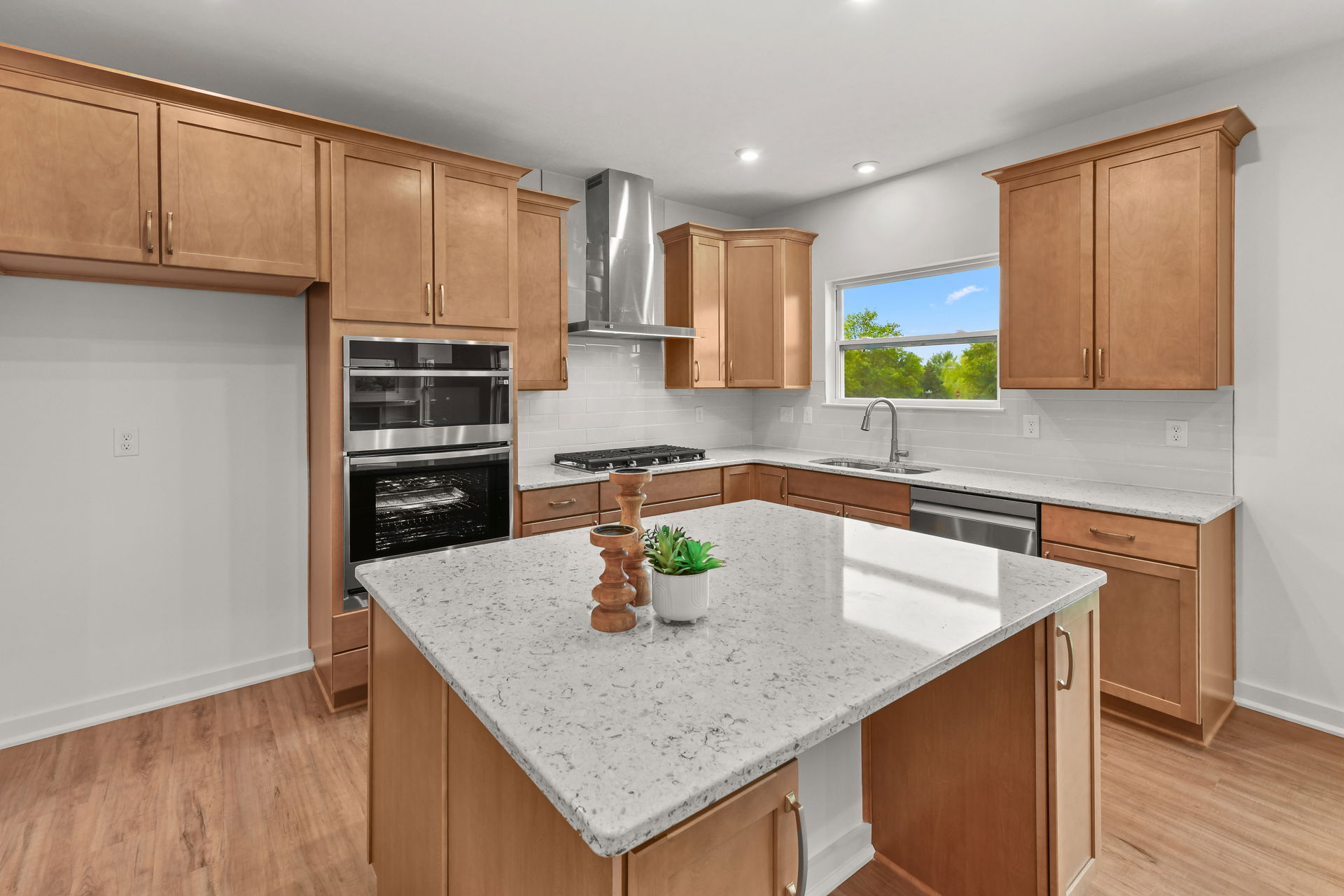 Modern kitchen with light wood cabinets, stainless steel appliances, and a large, granite-topped island.