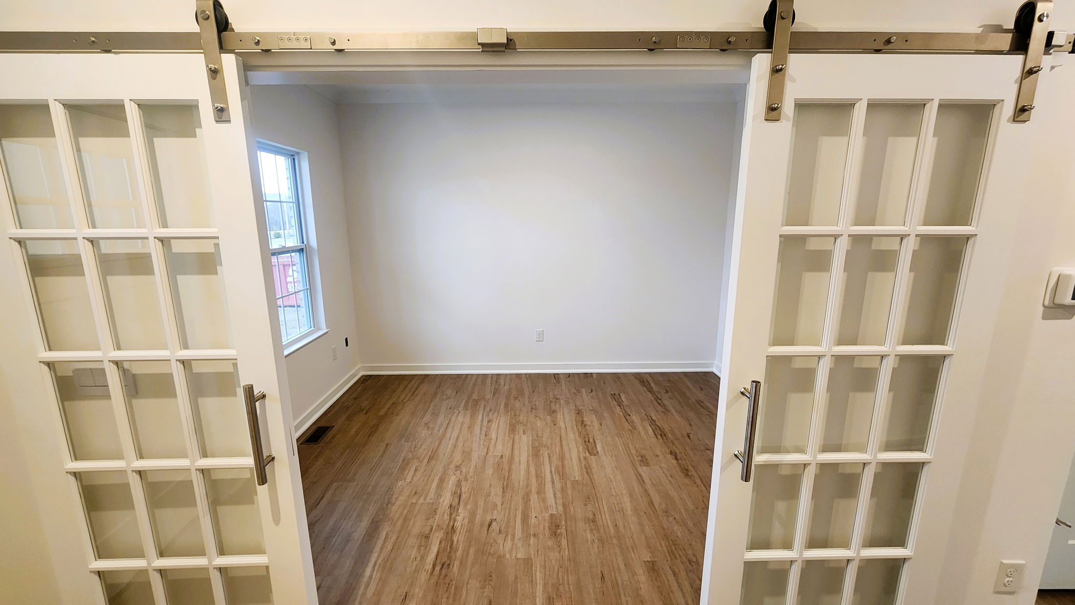 Interior view of a room with wooden flooring seen through stylish sliding glass doors.