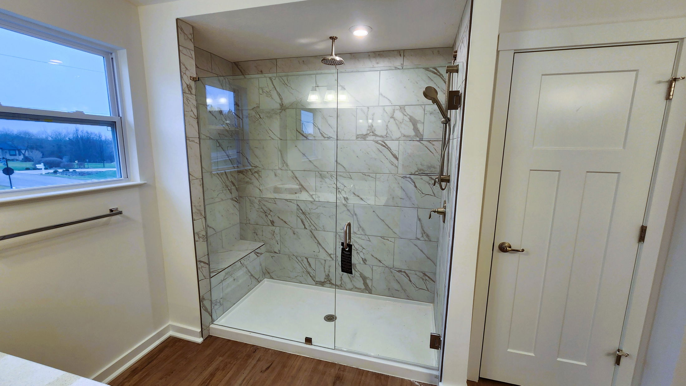 Modern bathroom featuring a glass shower enclosure with marble tile walls and a rain showerhead.
