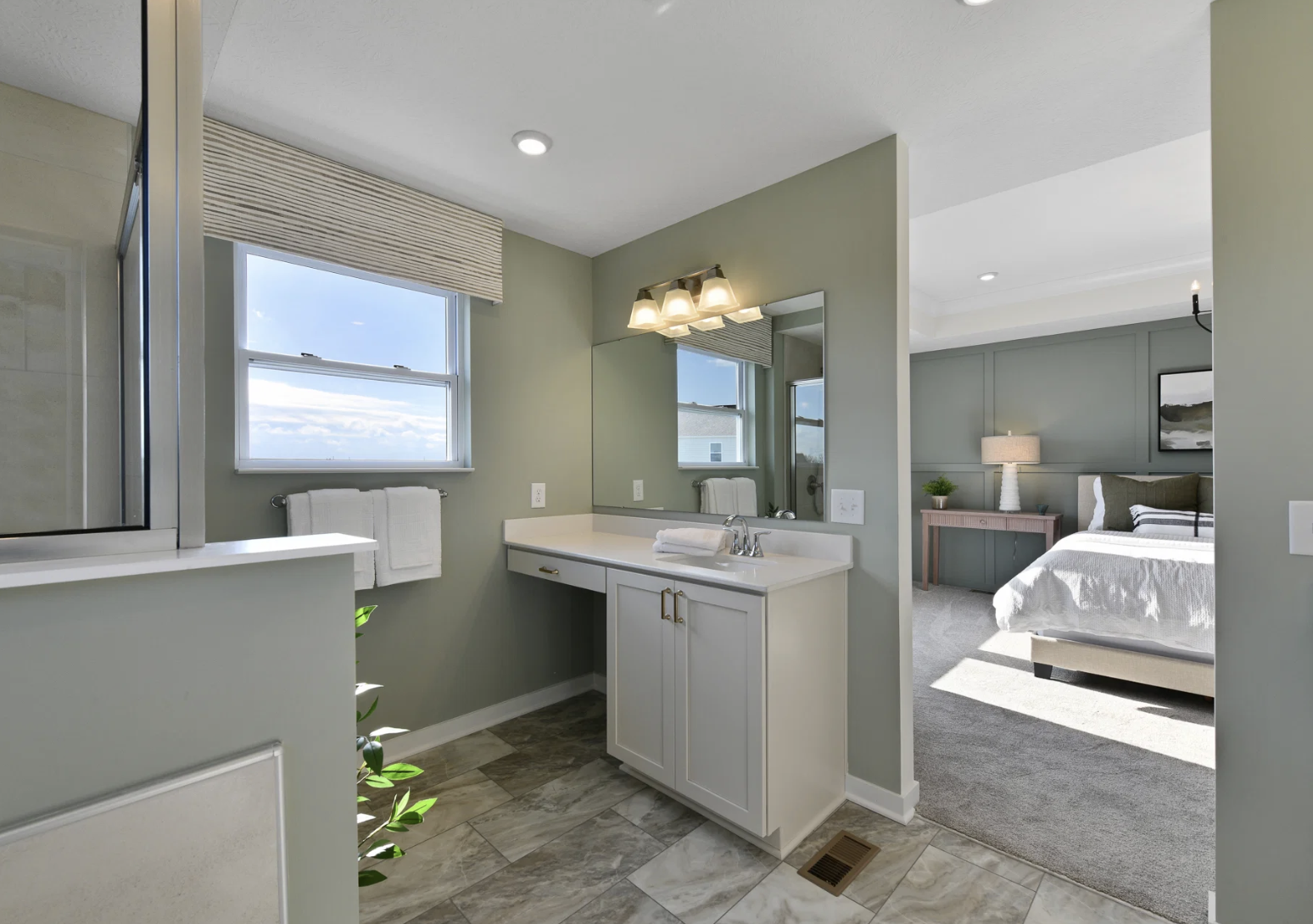 Modern bathroom with a sink, mirror, and window, adjacent to a bedroom.