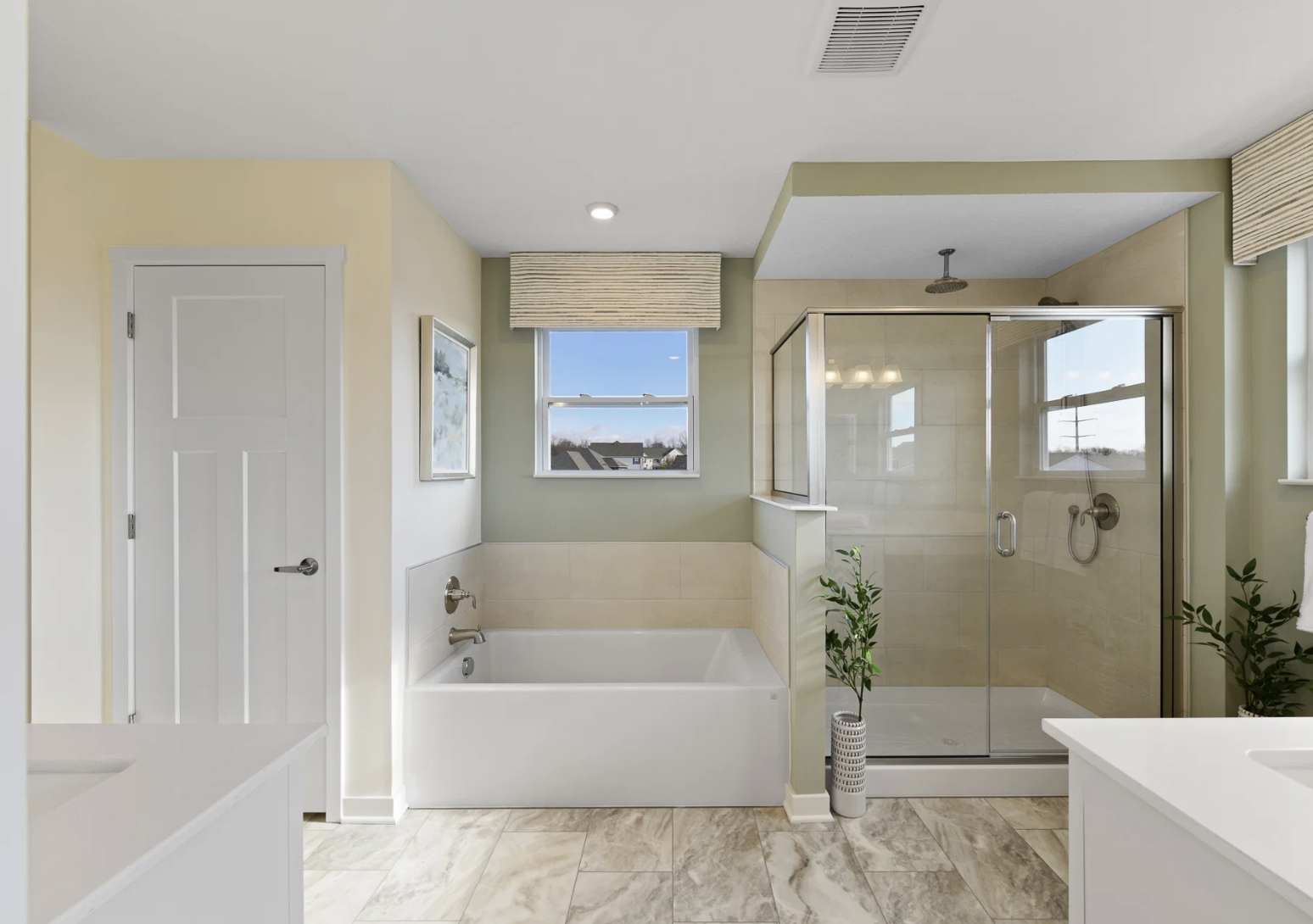 Modern bathroom featuring a bathtub, glass shower enclosure, and natural light from a window.