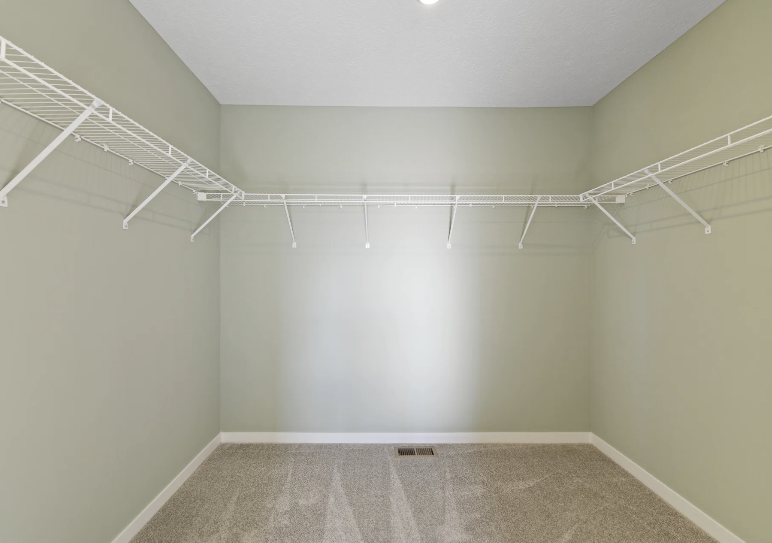 Empty walk-in closet with green walls and white wire shelving.