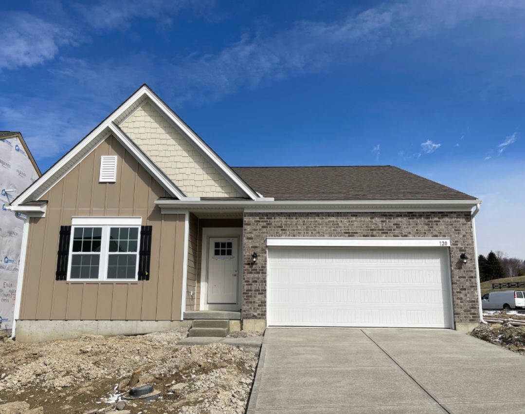 New modern-style house with a combination of brick and siding, featuring a spacious front porch and a two-car garage under a bright blue sky.