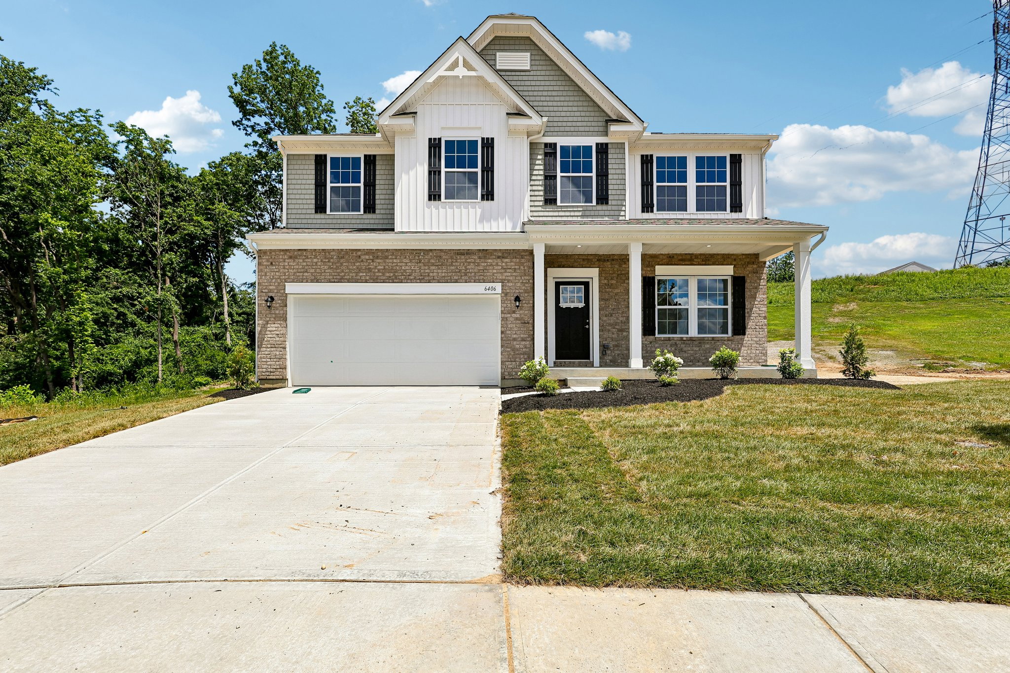 Two-story house with a mix of gray siding and brick exterior, a well-maintained lawn, and a concrete driveway.