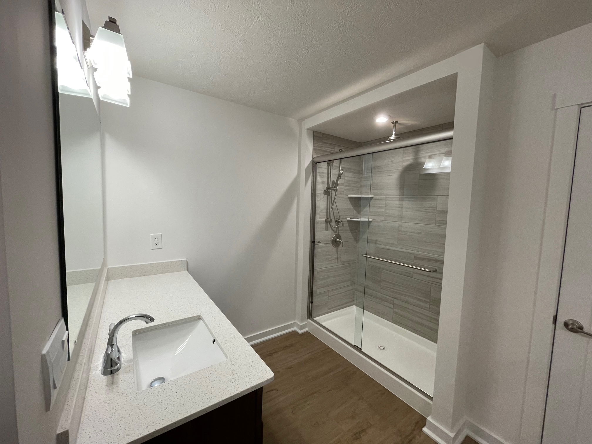 Modern bathroom featuring a glass-enclosed shower with overhead lighting and a sleek white vanity with a chrome faucet.