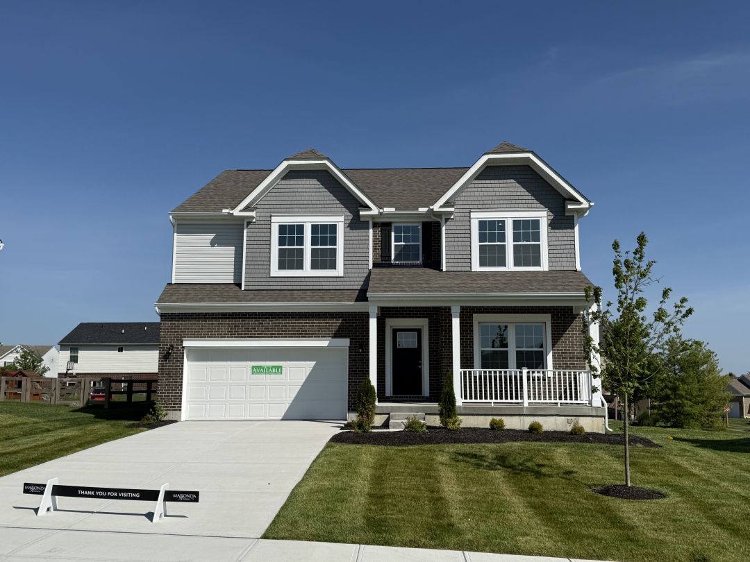 Modern two-story suburban home with gray siding and a well-maintained lawn against a clear blue sky.