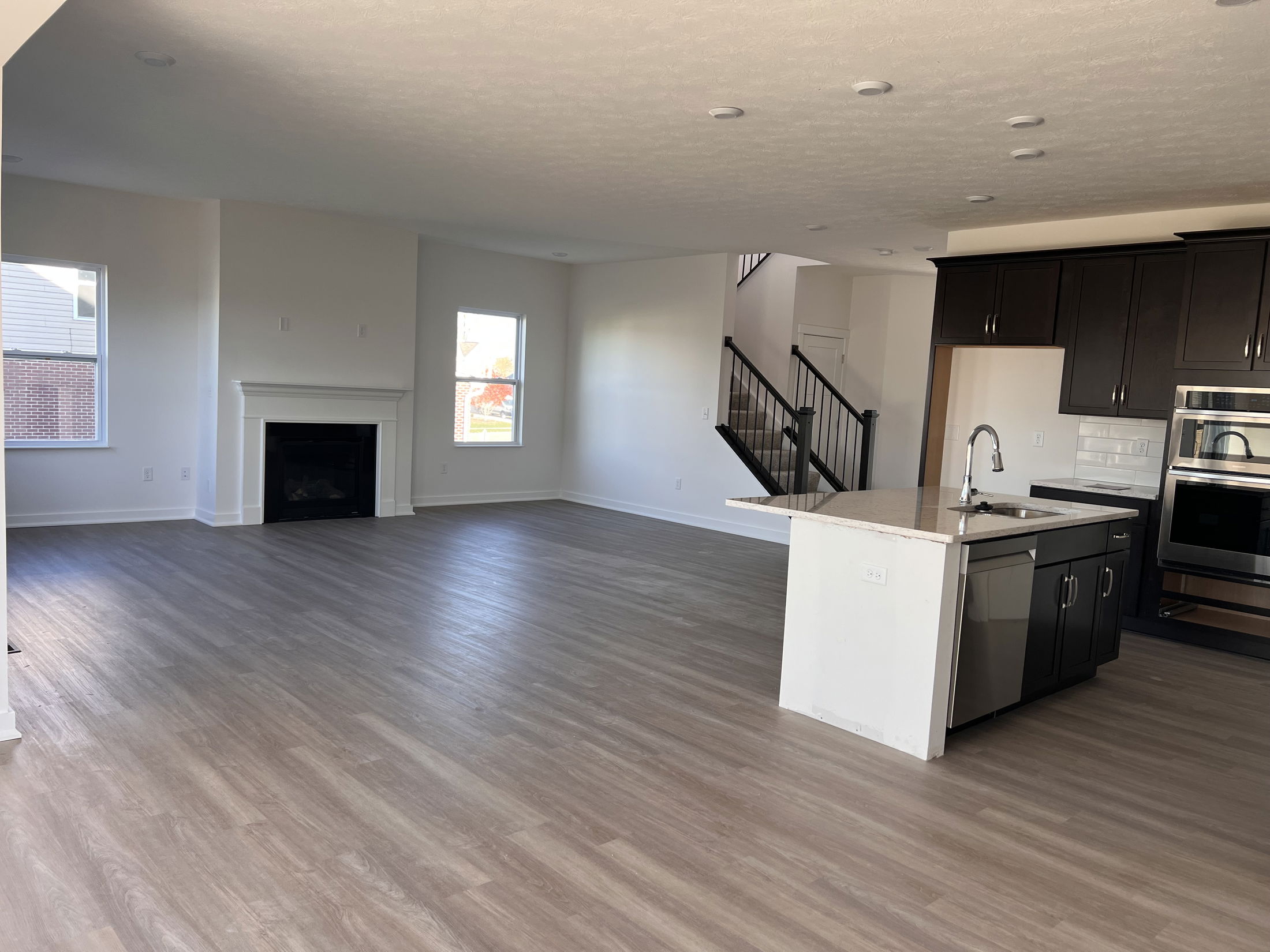 Modern open-concept living area with hardwood floors, a kitchen island, and a fireplace.